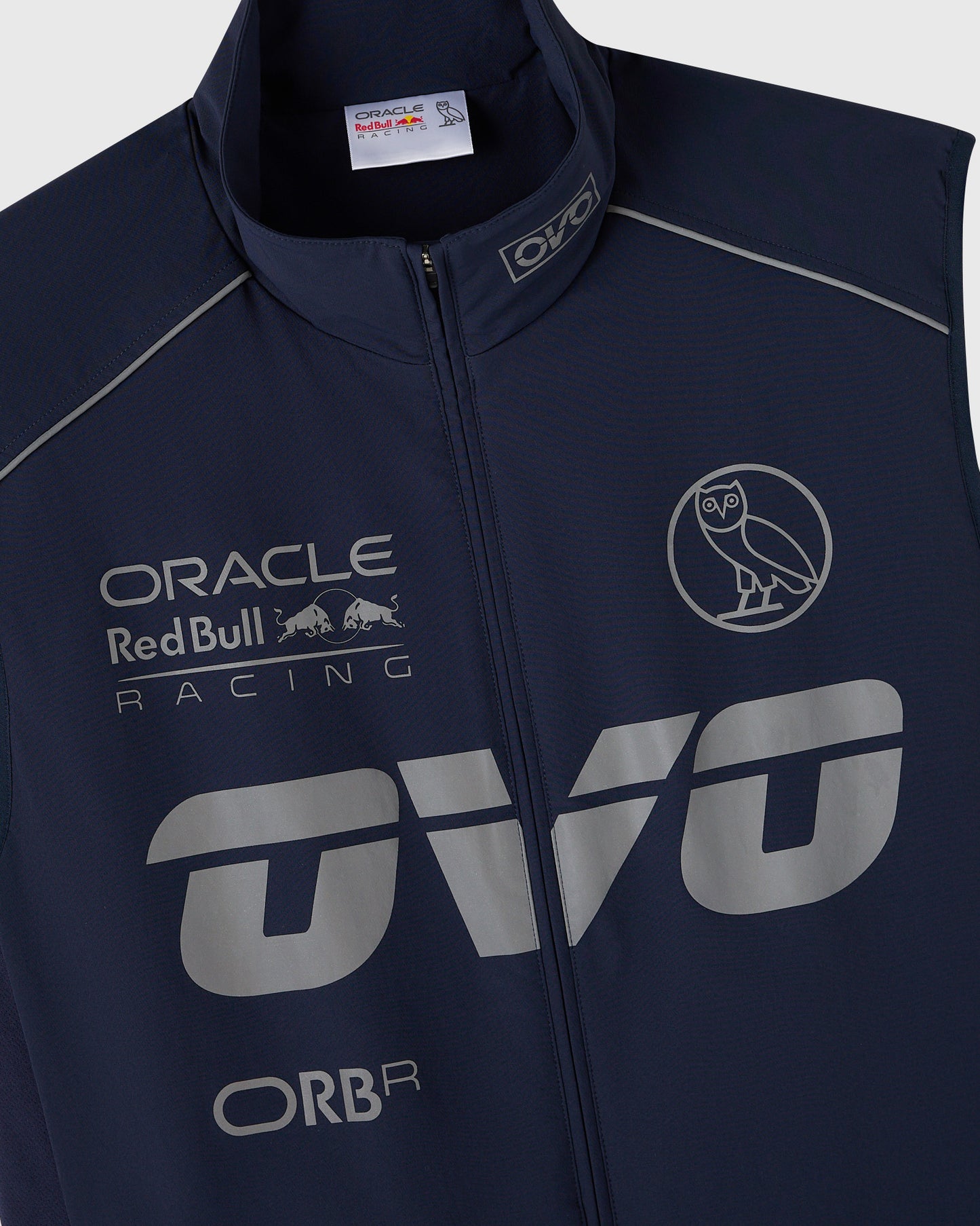 Navy nylon vest with reflective Oracle Red Bull Racing logos, owl graphic, and piping details.