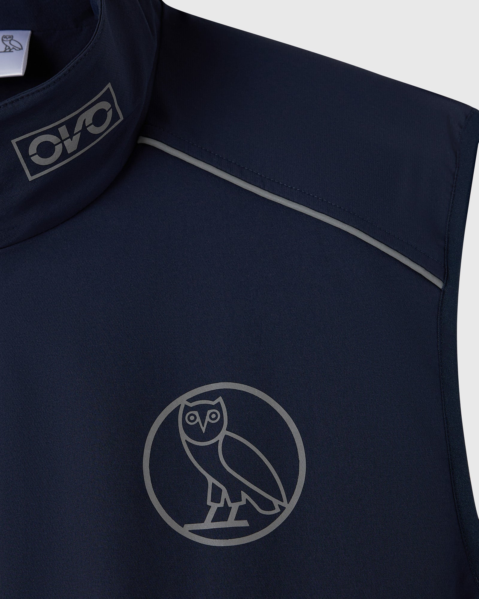 Navy nylon vest with reflective owl logo on chest and reflective stripe detail on shoulder.