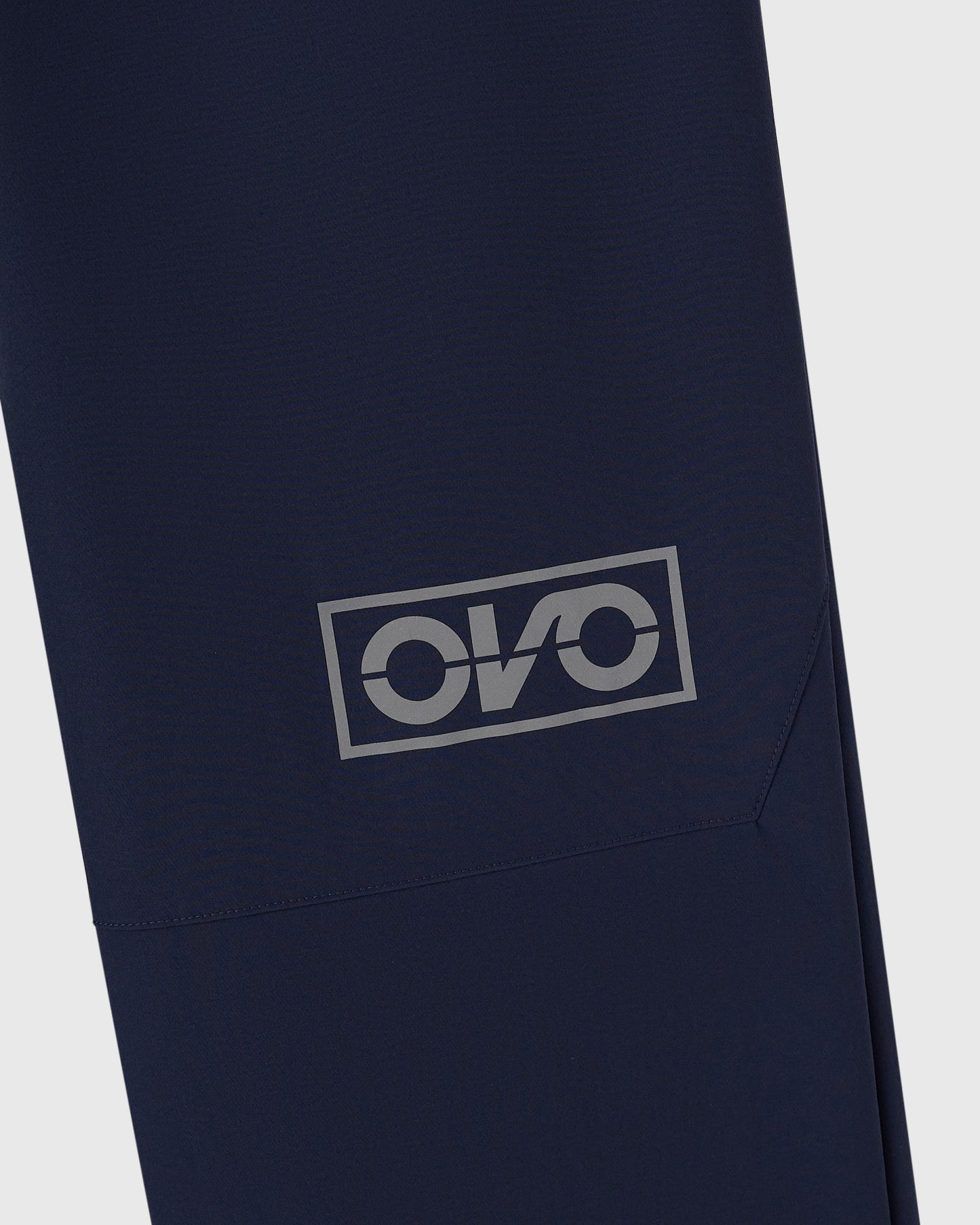 Navy nylon pants with reflective logo print on thigh pocket.