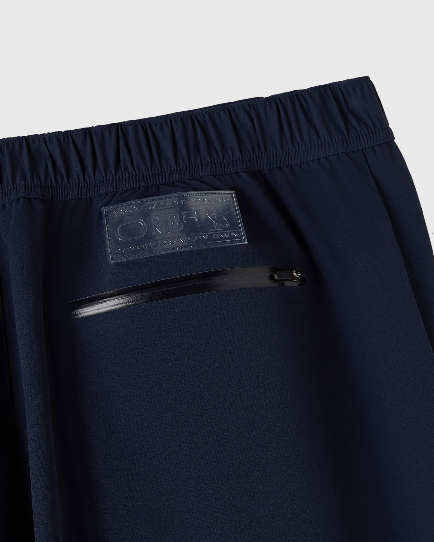Navy nylon pant with reflective print detail and zippered pocket at waistband.