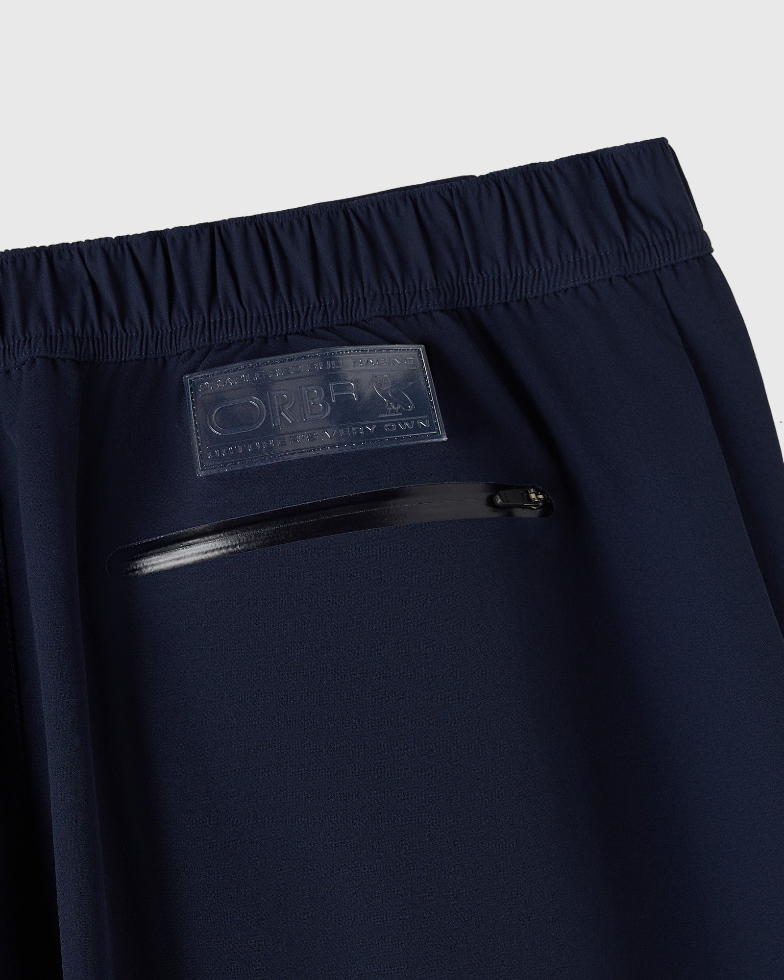 Navy nylon pant with reflective print detail and zippered pocket at waistband.
