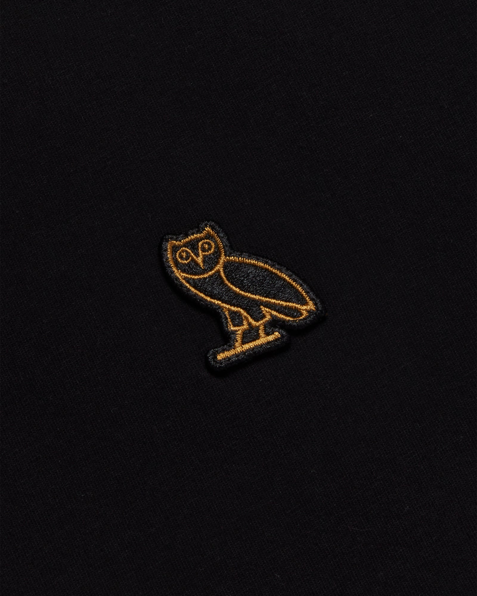 Black long-sleeve tee with gold embroidered owl design on chest.