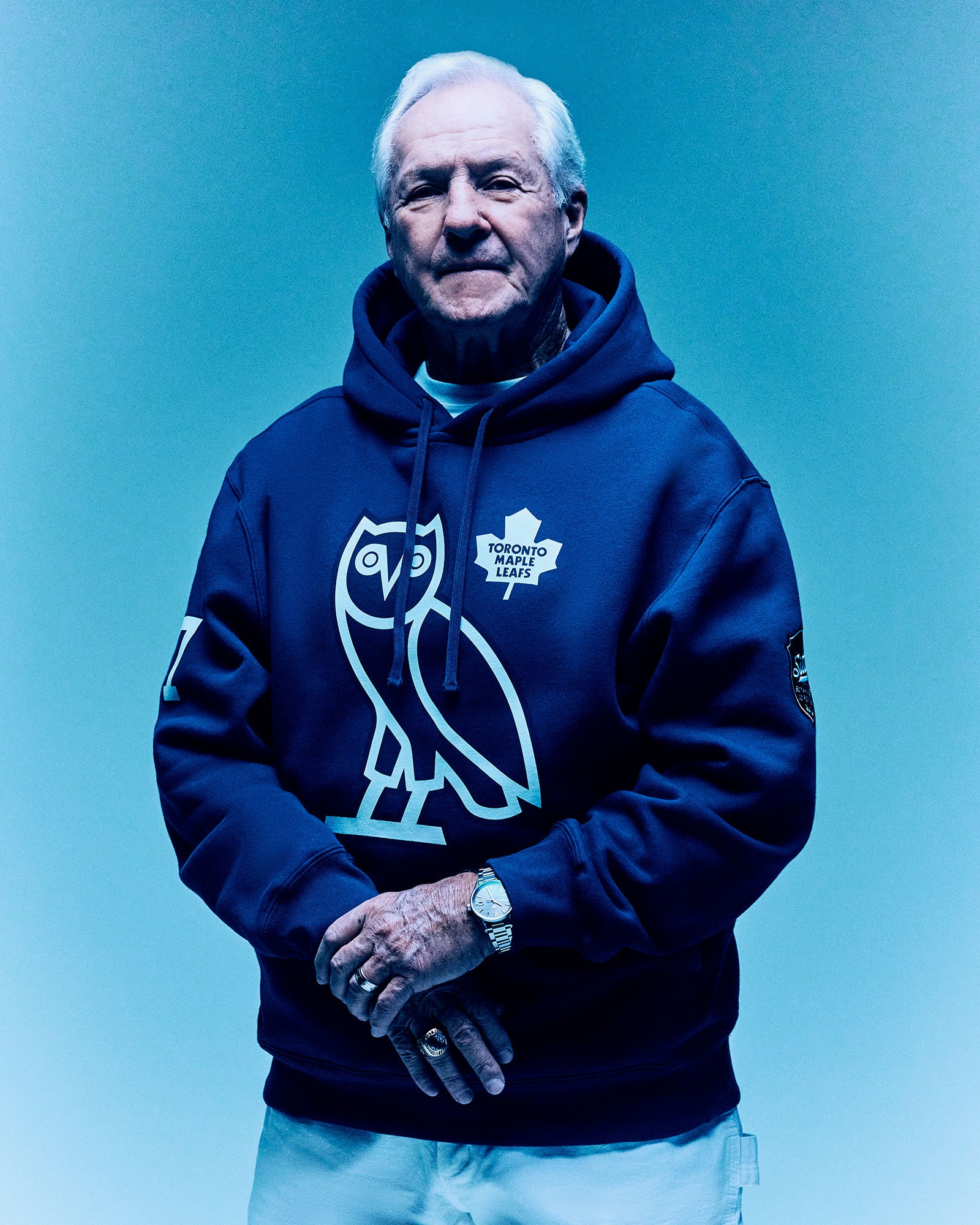 Man wearing a blue October's Very Ownhoodie with a logo on a blue background