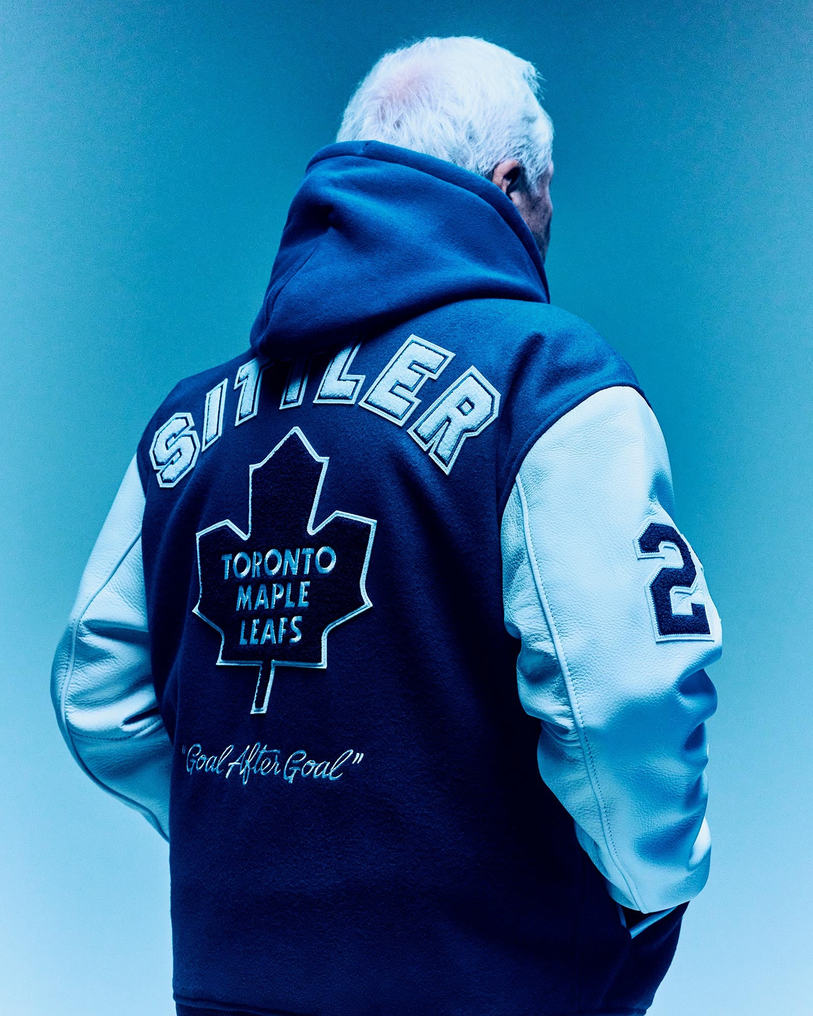 Darryl Sittler wearing a Toronto Maple Leafs jacket with 'Sinner' branding on a blue background by October's Very Own