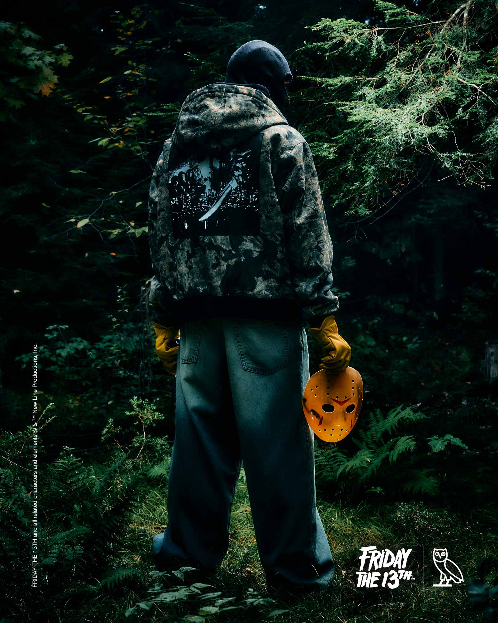 Person in camouflage October's Very Own x Friday the 13th jacket holding a Halloween pumpkin in a forest, with 'Friday the 13th' branding.