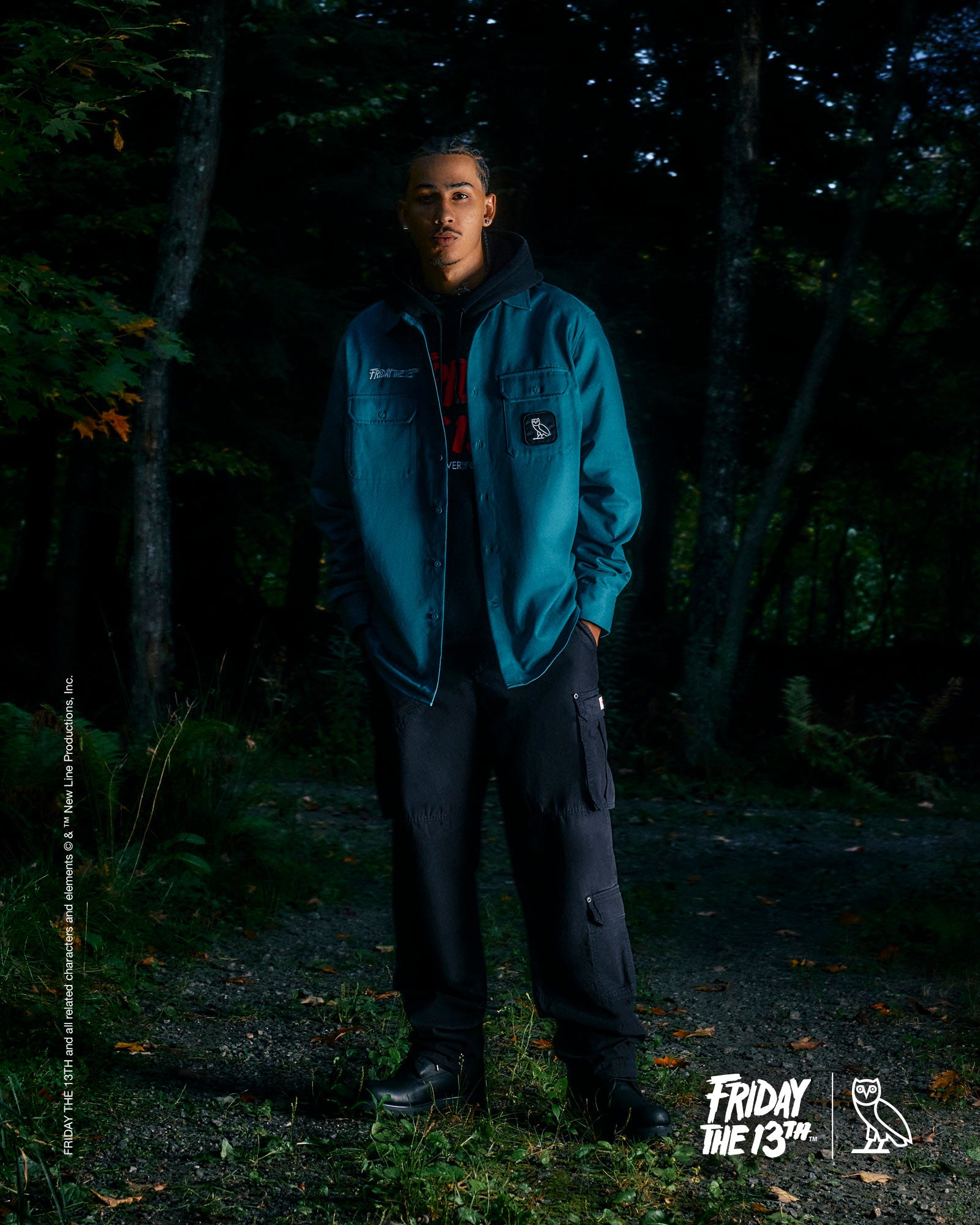 Person wearing a October's Very Own blue jacket standing in a dark forest with 'Friday the 13th' branding.
