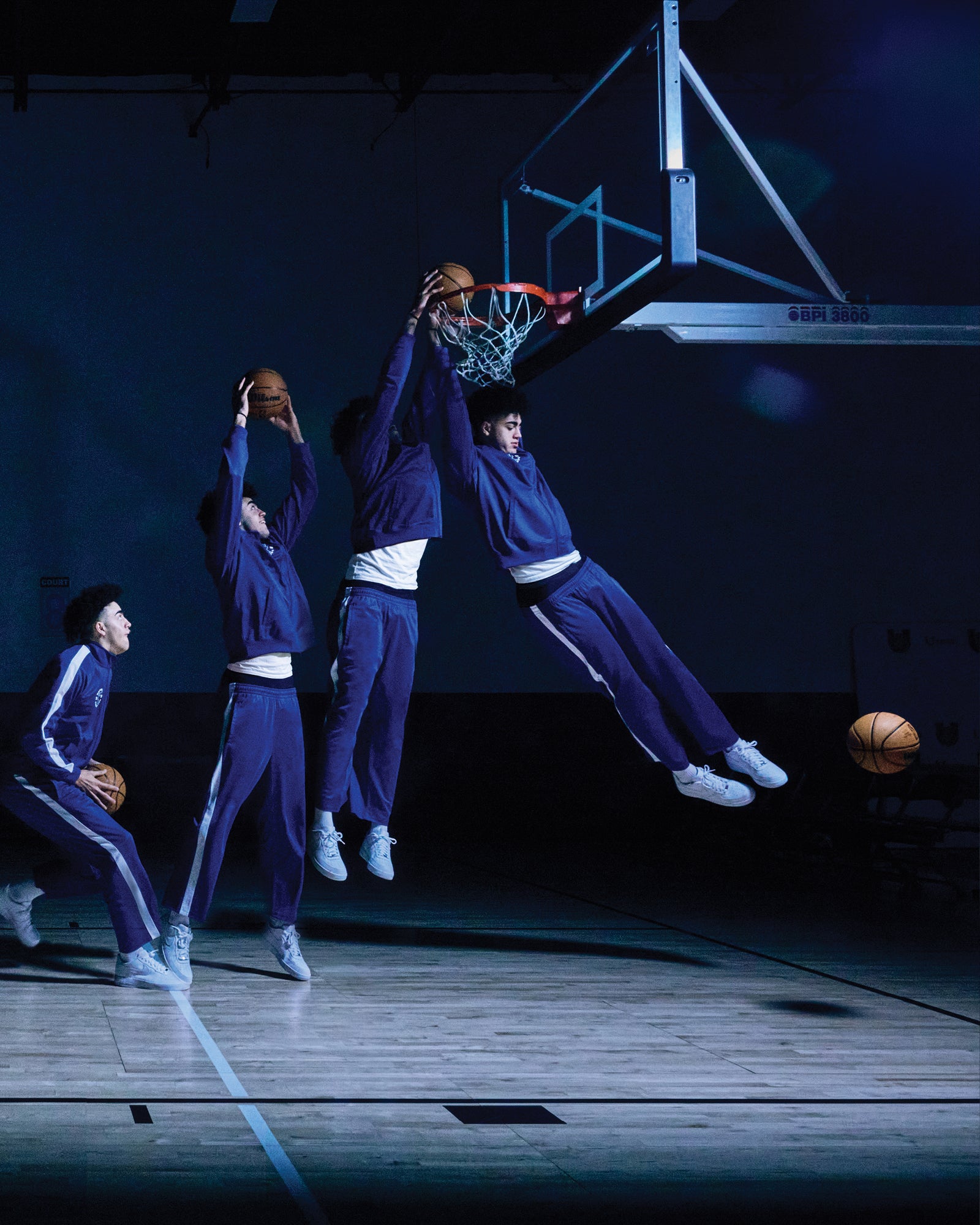 Basketball players in action on a court with a dark background