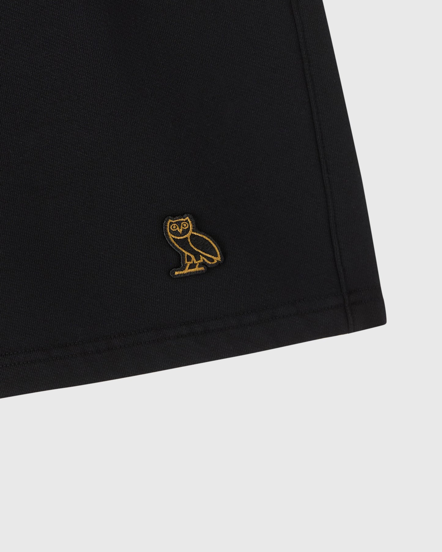 Black sweatshort with gold owl embroidery on thigh.