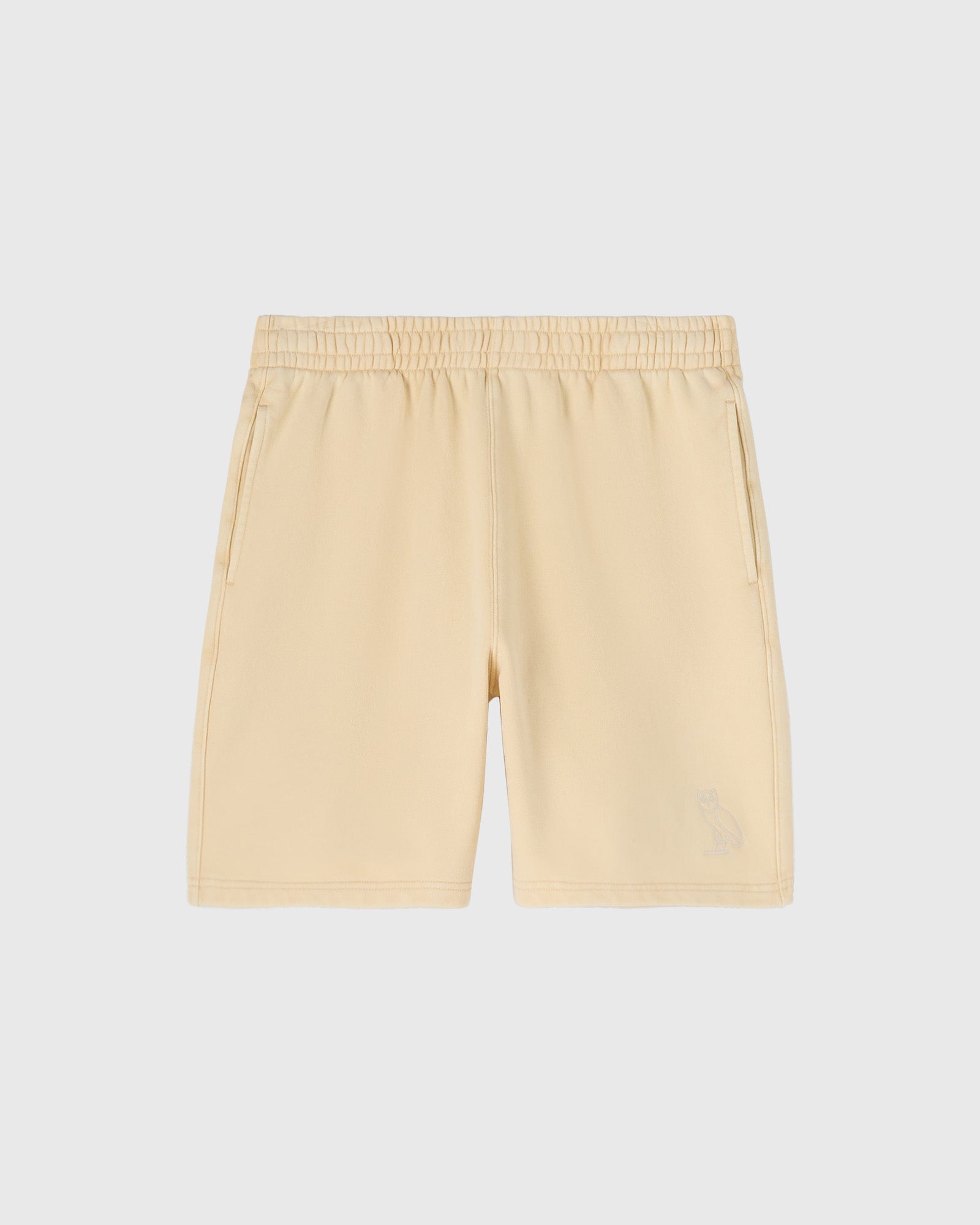 Cream-colored shorts with elastic waistband, side pockets, and center seam detail.