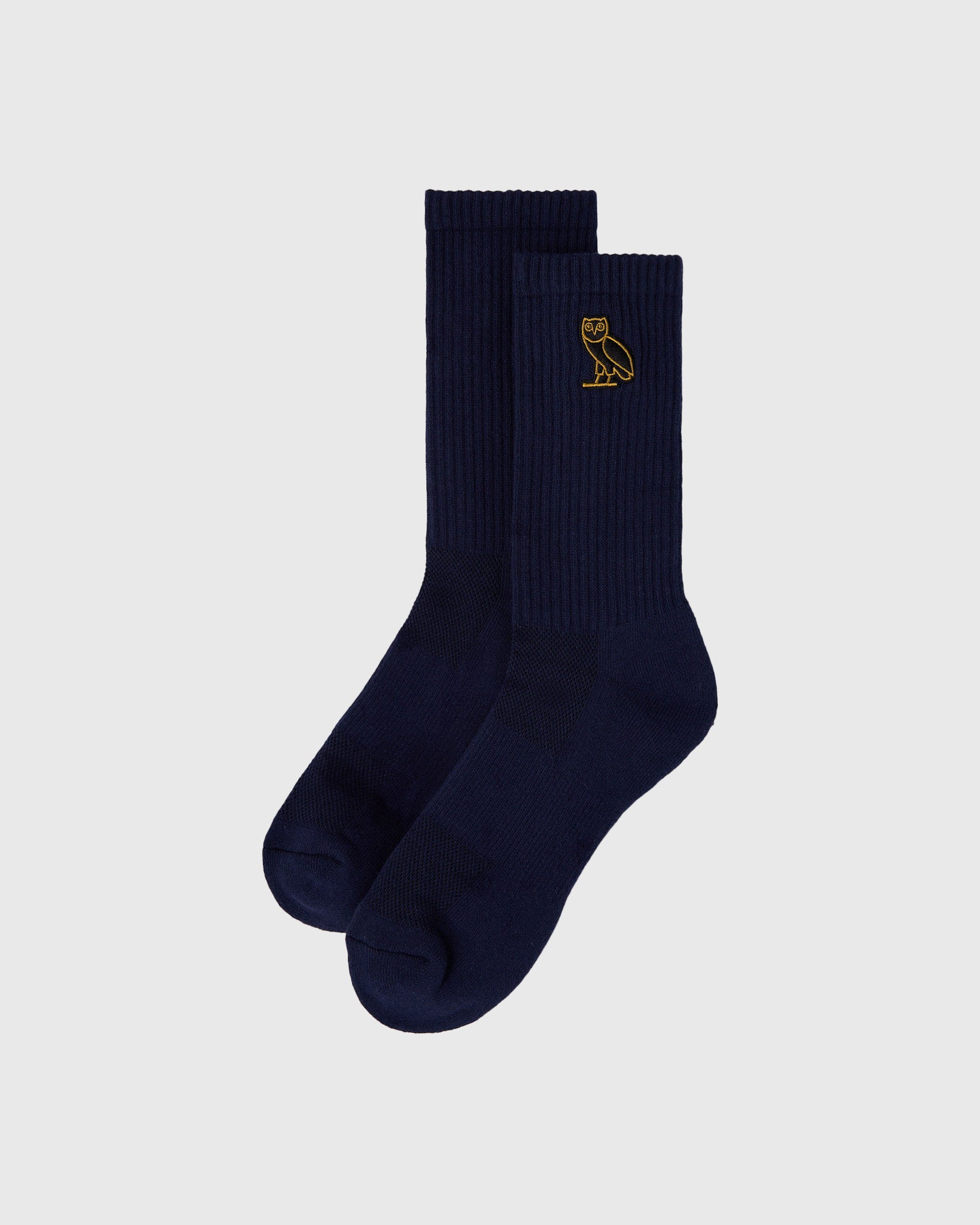 Pair of navy ribbed crew socks with small gold owl embroidery on the calf.