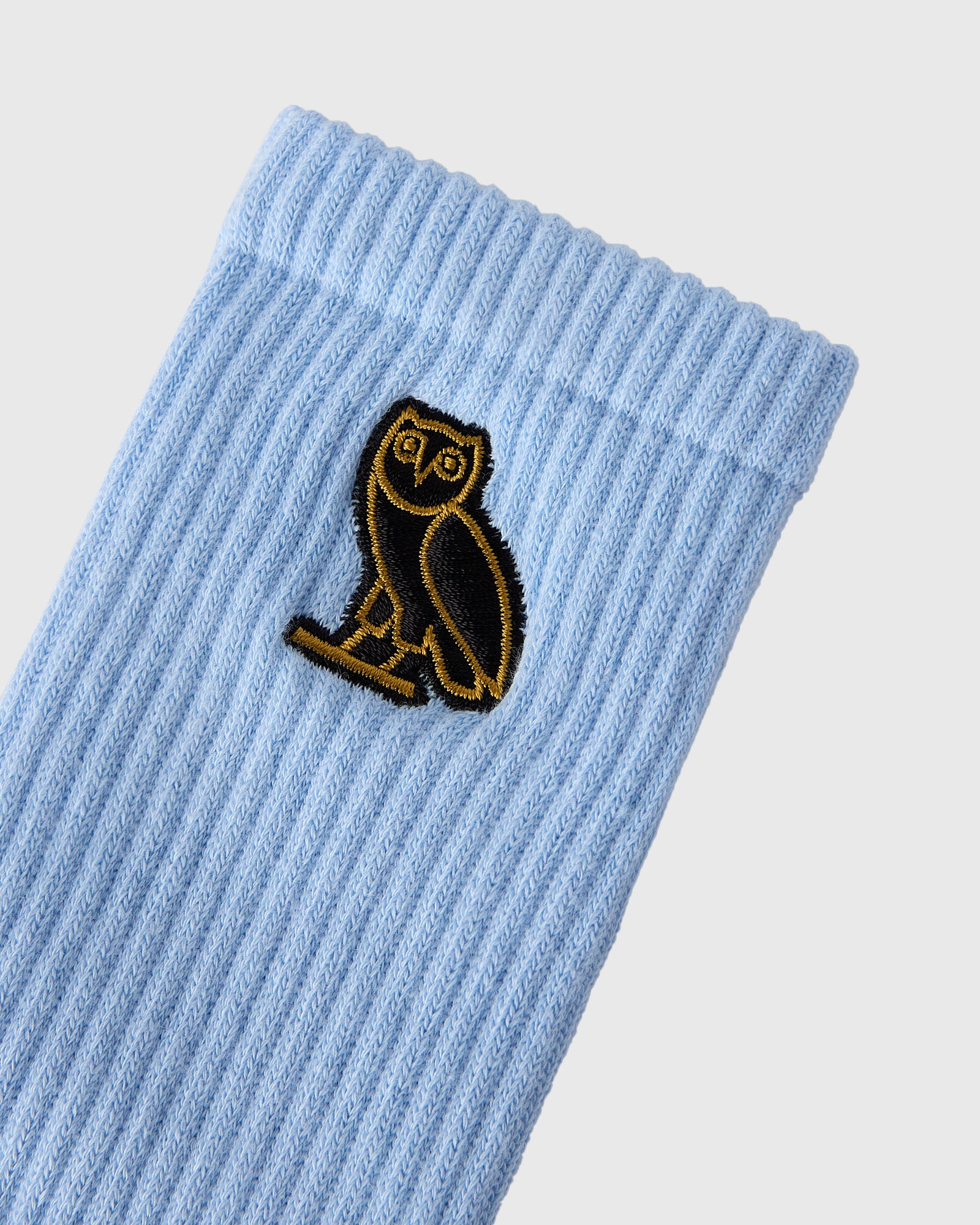 Light blue ribbed sock with black and gold embroidered owl patch.