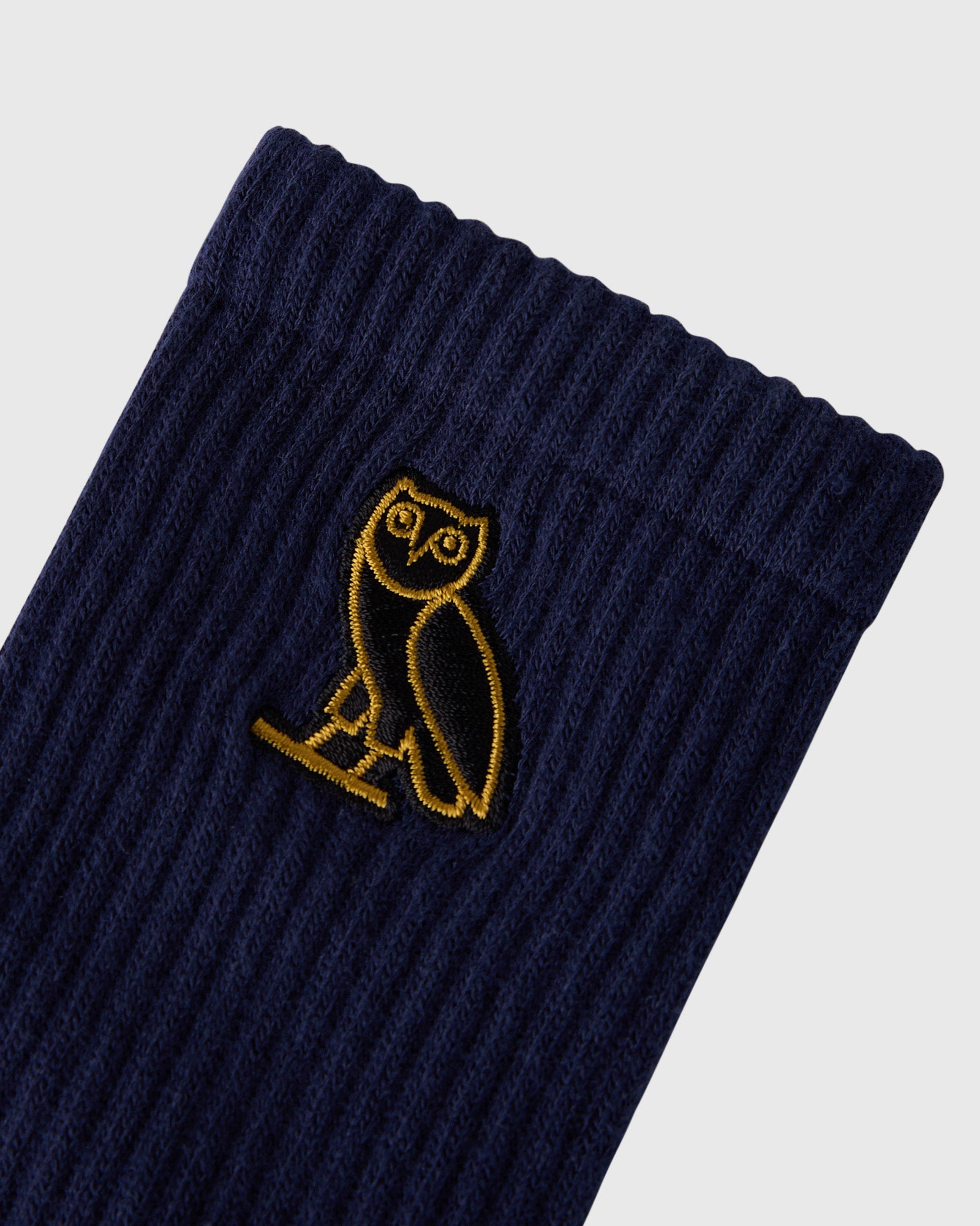 Navy ribbed socks with yellow owl embroidered logo on the leg.