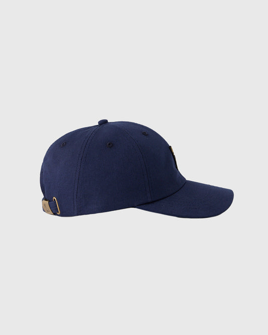 Navy baseball cap with six-panel crown, curved bill, and tan adjustable strap closure at back.