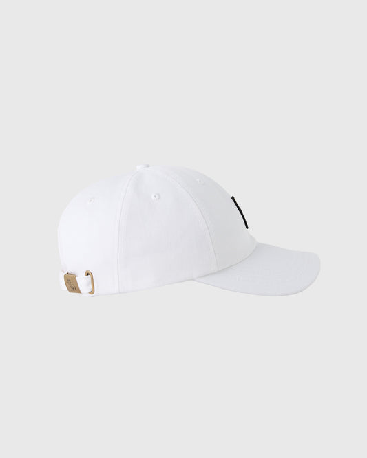 White baseball cap with curved bill, ventilation eyelets, and tan back strap with metal closure.