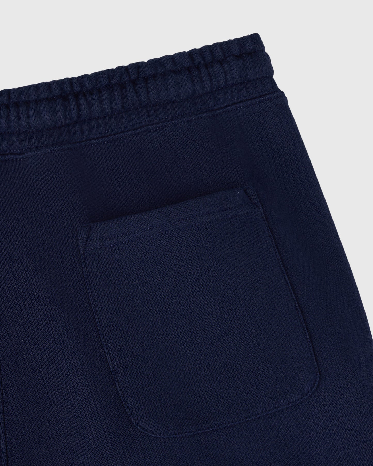 Navy sweatpant with ribbed waistband, open hem, and patch pocket detail.