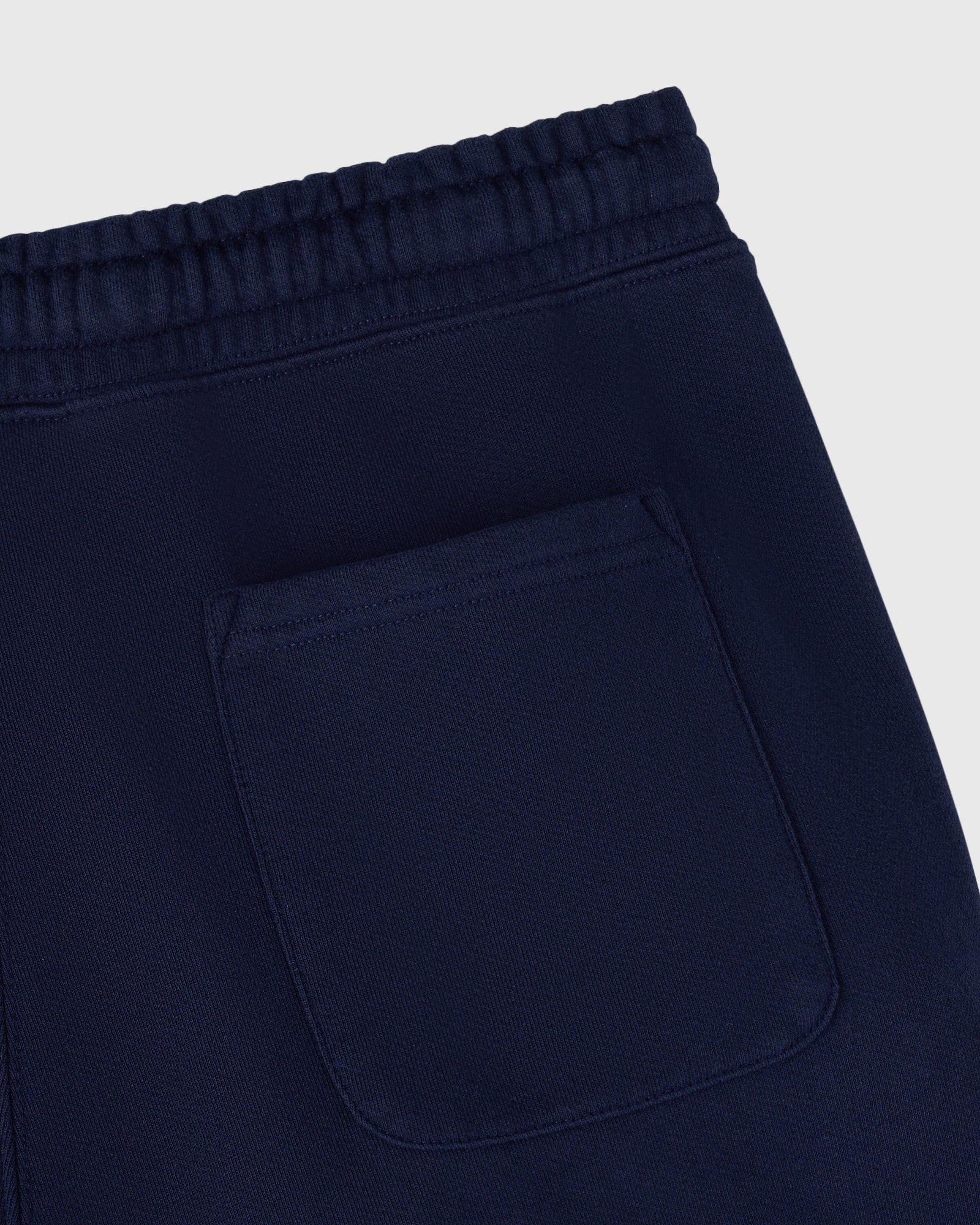 Navy sweatpant with ribbed waistband, open hem, and patch pocket detail.