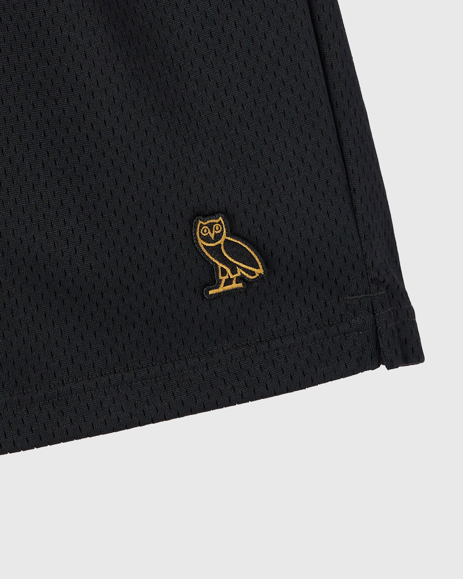 Black mesh shorts with gold owl embroidery on the thigh and ribbed hem detail.