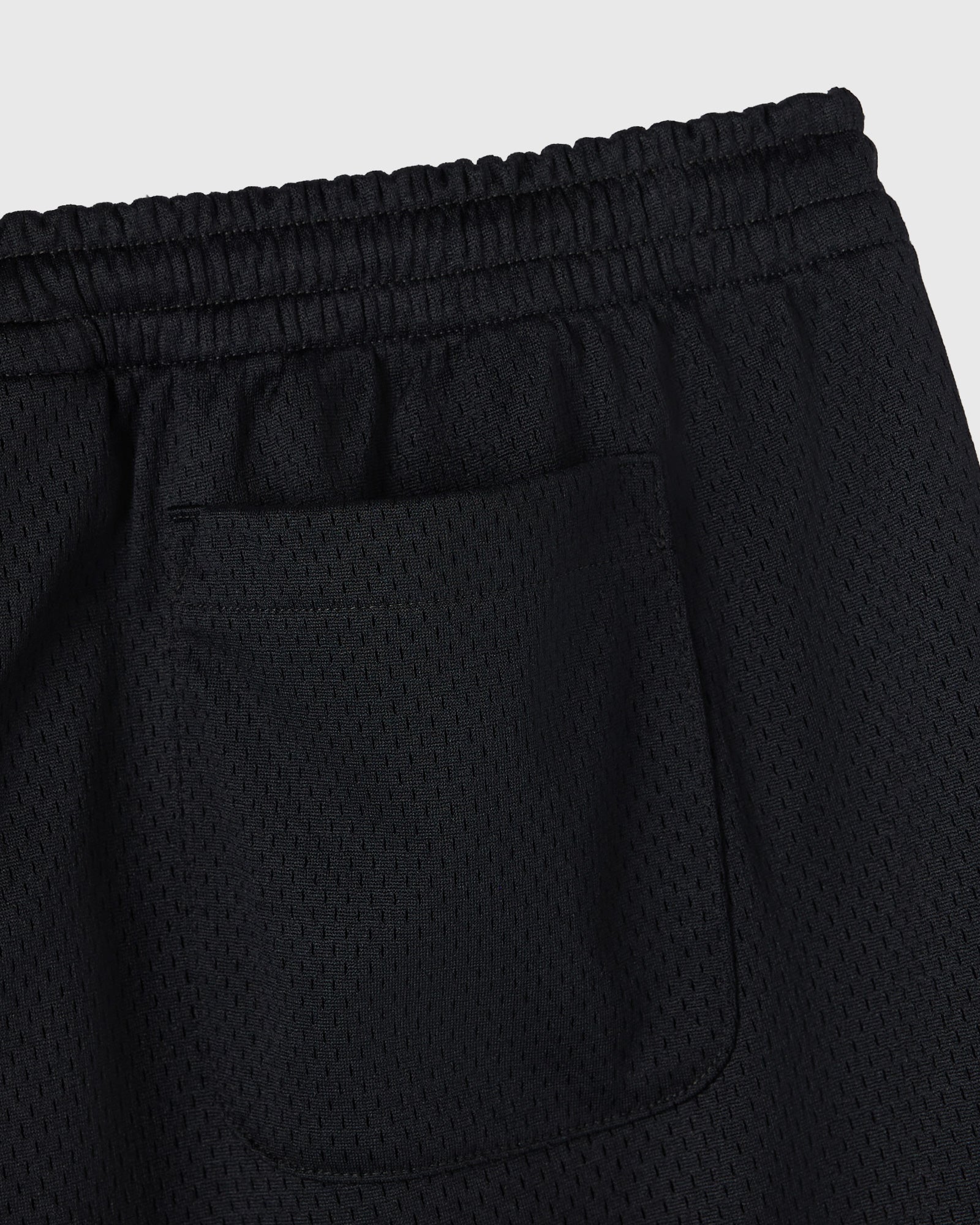 Black mesh shorts with elastic waistband and front pocket detail.