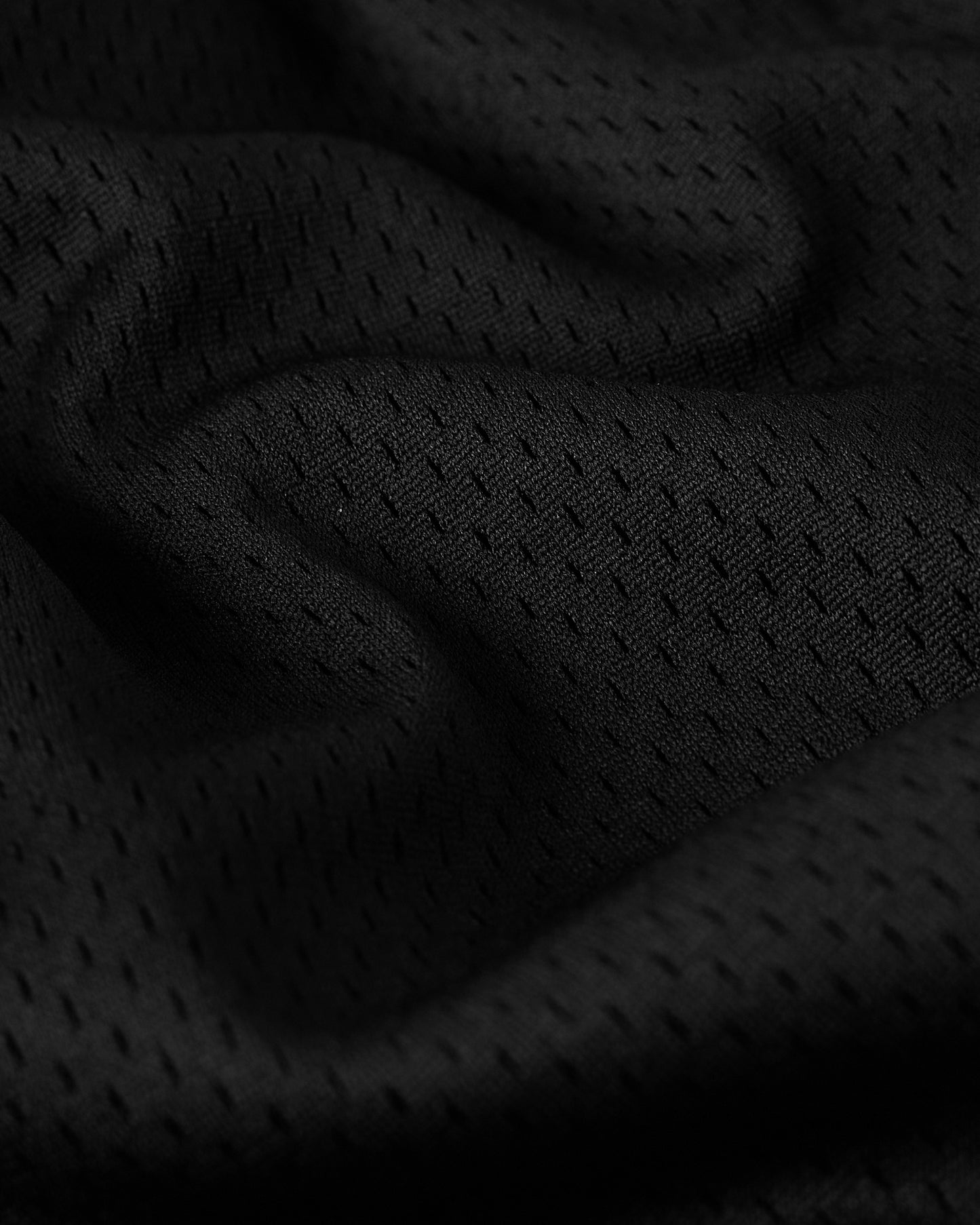 Close-up of black mesh fabric with textured weave pattern and folded sections.