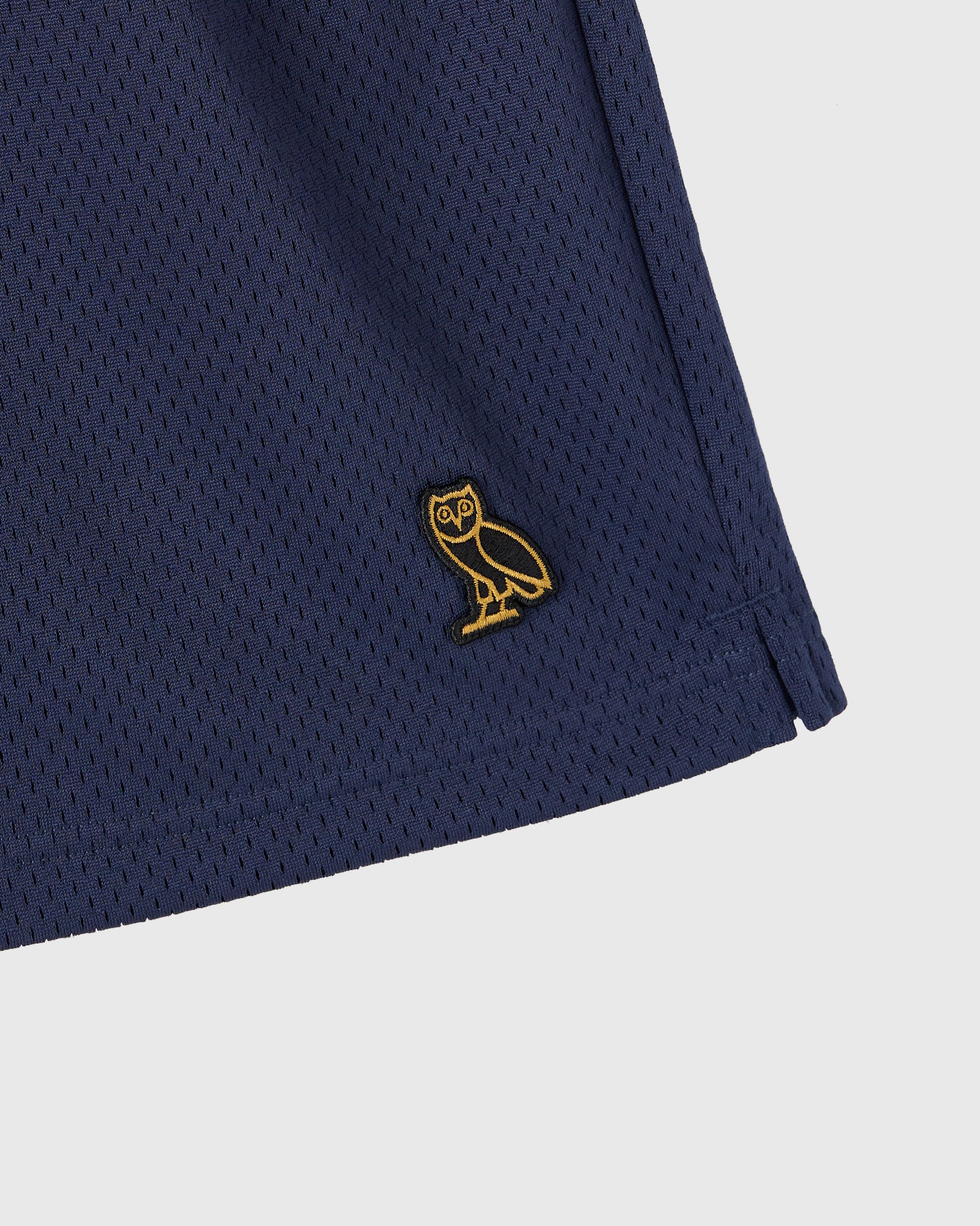 Navy mesh shorts with gold owl embroidered logo on thigh.