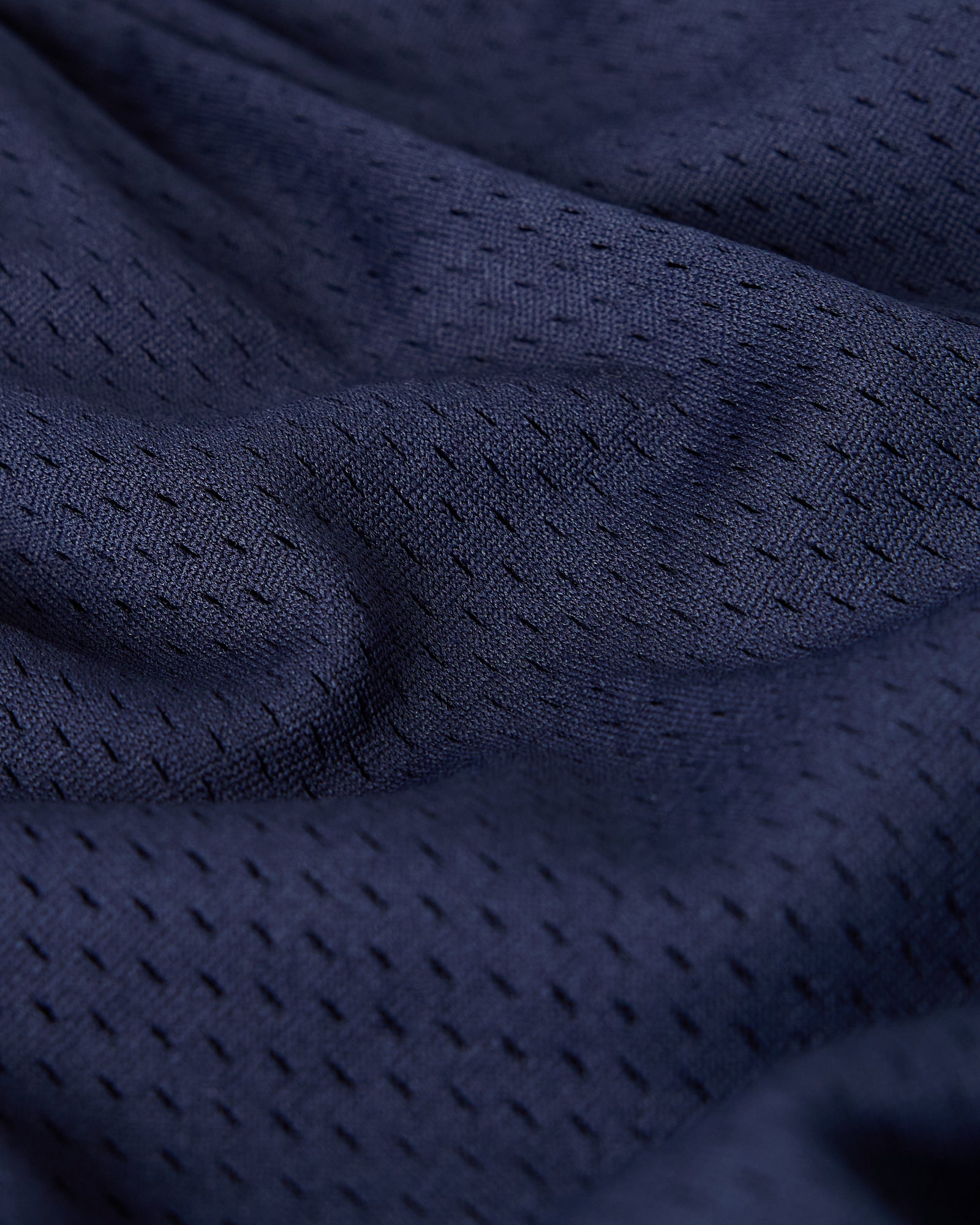 Close-up of navy mesh fabric with textured weave pattern and visible breathable openings.