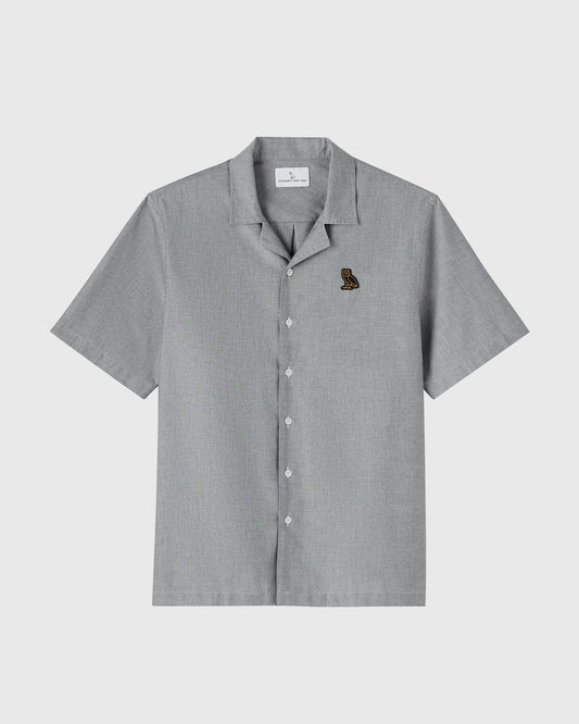 Gray Oxford camp shirt with short sleeves, camp collar, white buttons, and small embroidered logo on chest.