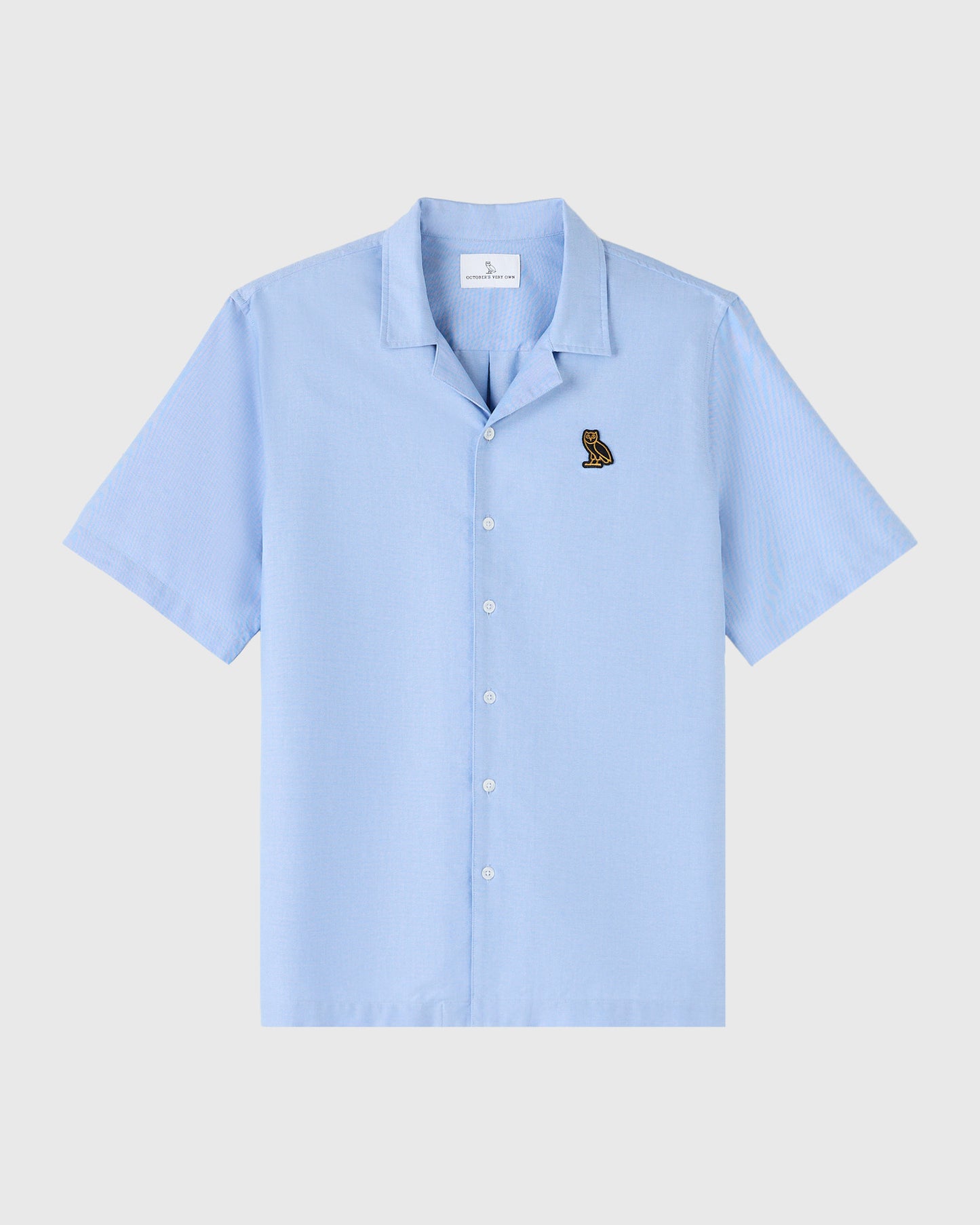 Light blue short-sleeve camp shirt with camp collar and small owl embroidery on chest.