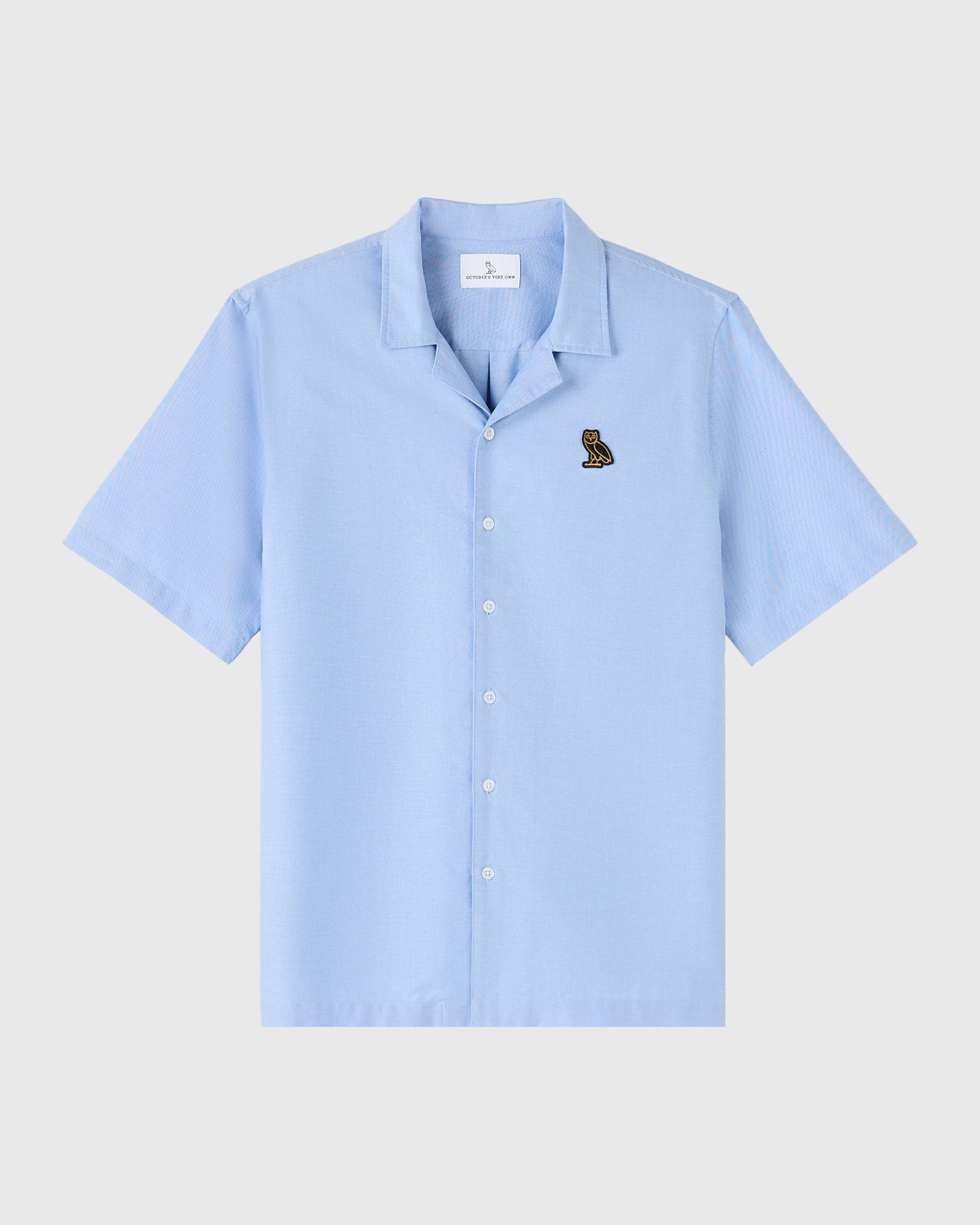 Light blue short-sleeve camp shirt with camp collar and small owl embroidery on chest.