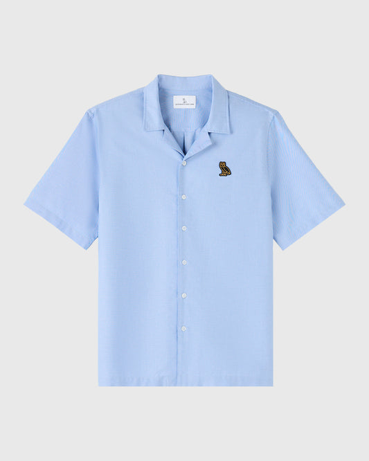 Light blue short-sleeve camp shirt with camp collar and small owl embroidery on chest.