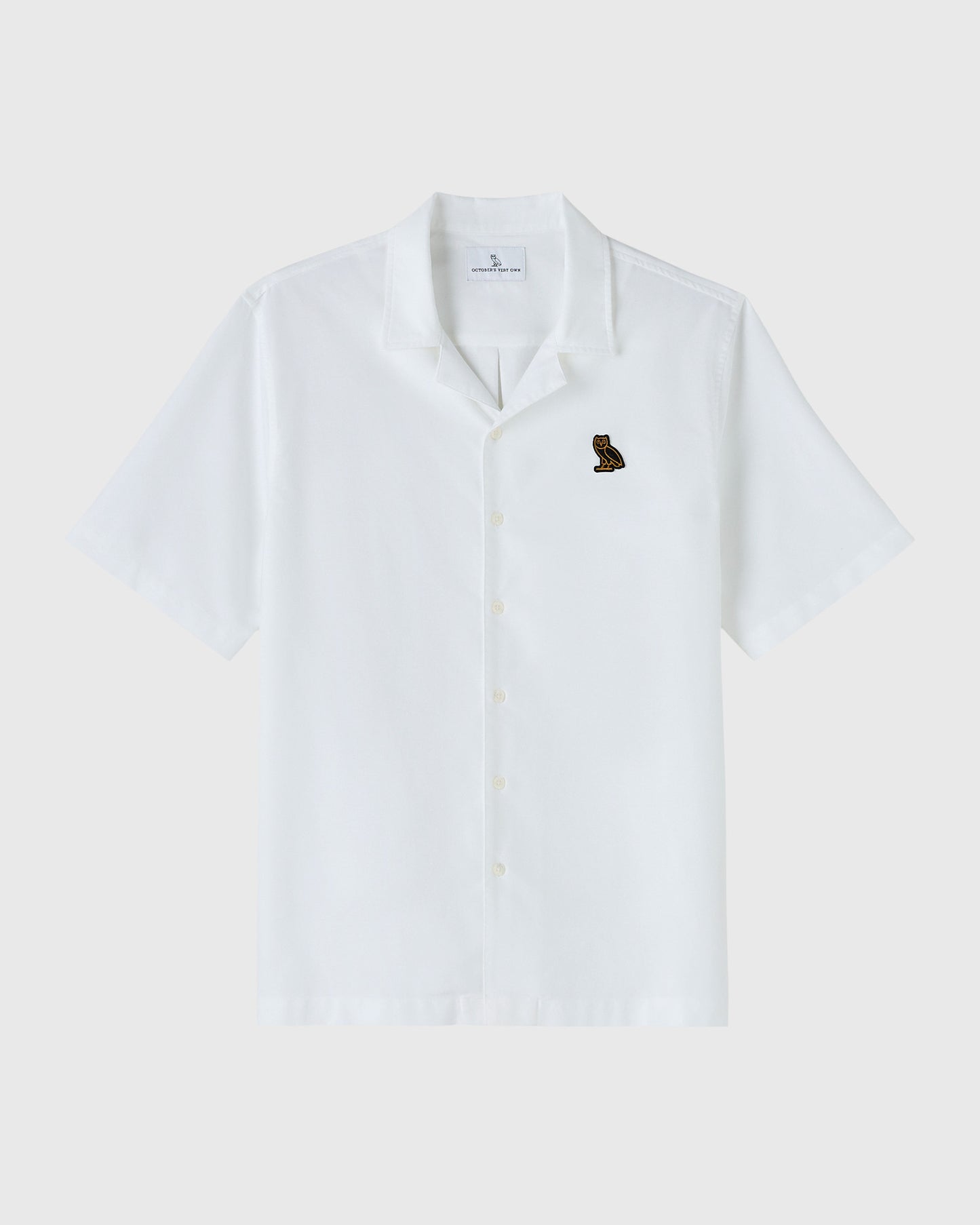 White short-sleeve camp shirt with button front closure and small embroidered bird logo on chest.