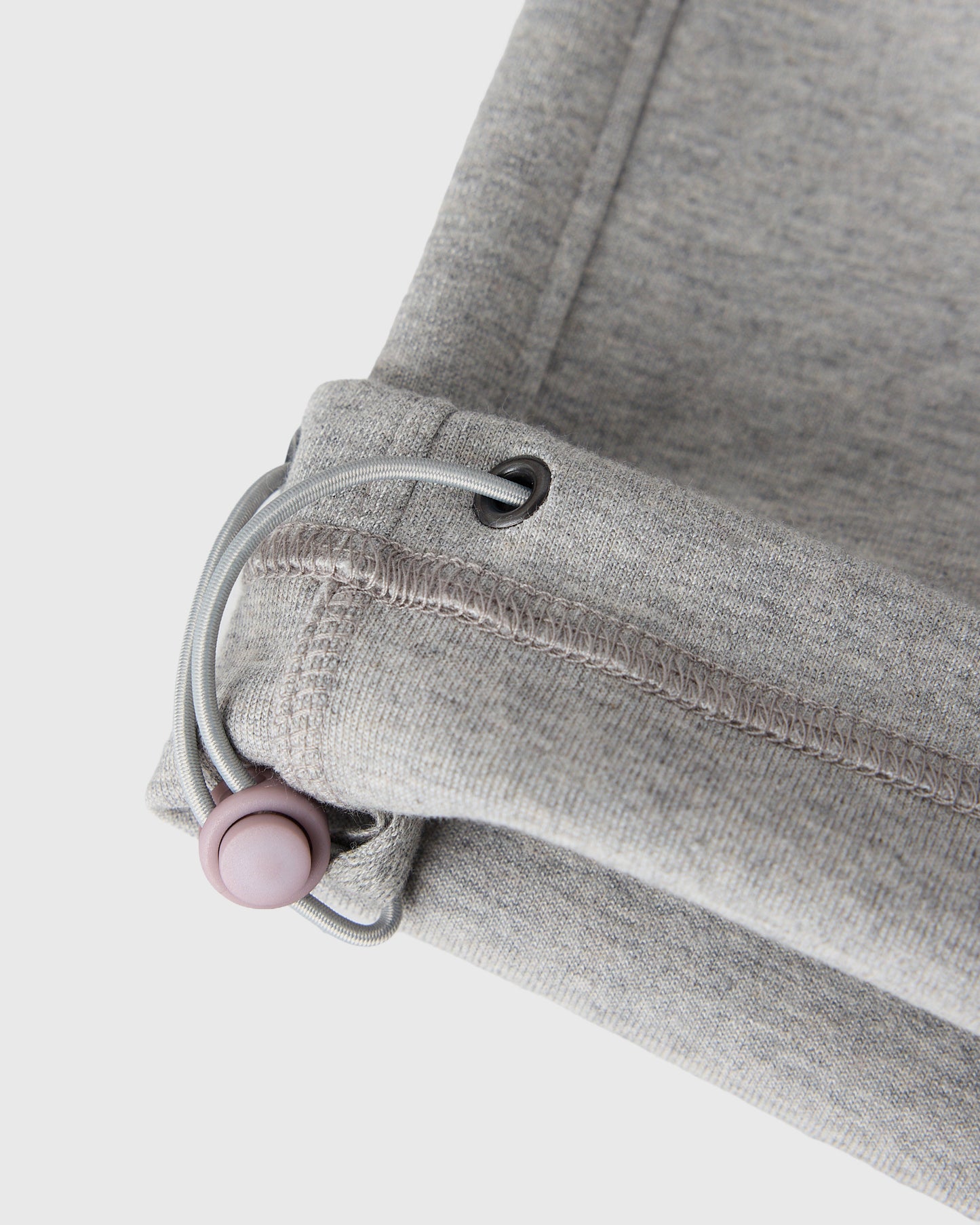 Heather grey sweatpants with ribbed cuffs, drawstring, and pink toggle detail at the waistband.