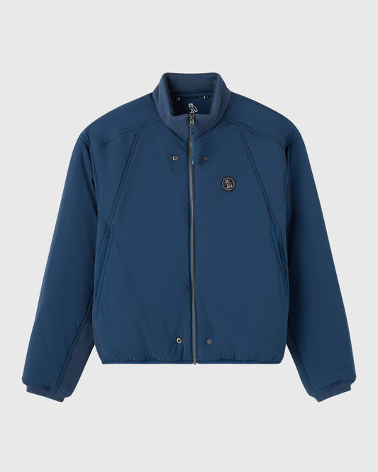 Dark blue zip-up jacket with stand collar, snap pockets, and circular logo patch on chest.