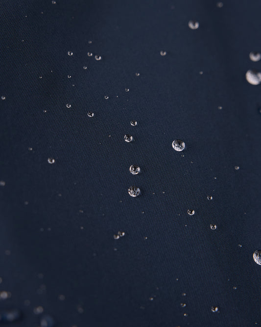 Water droplets beading on royal navy twill fabric surface.