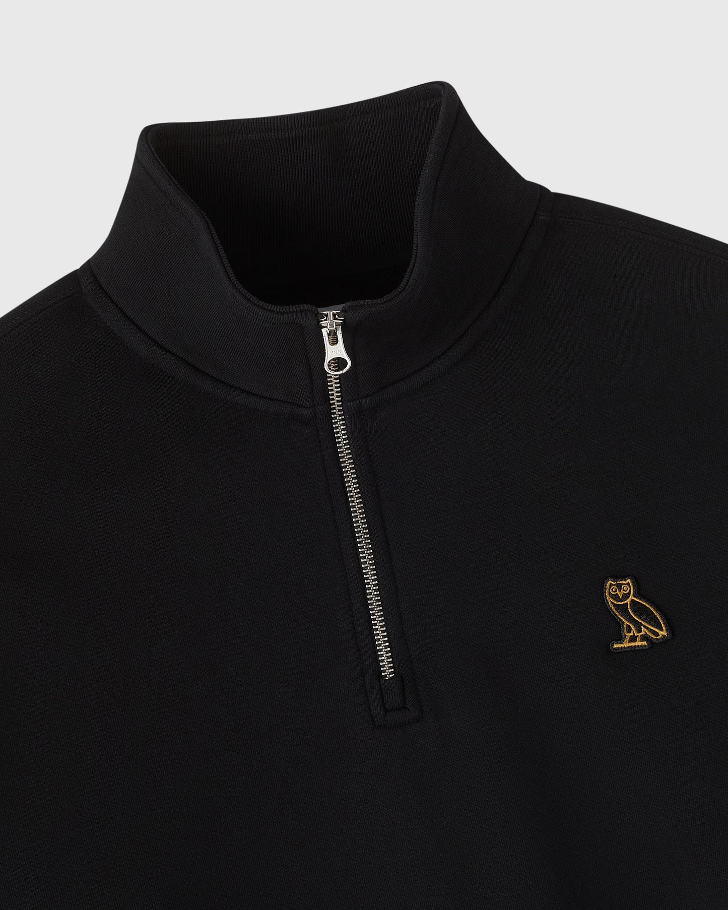 Black quarter zip mockneck sweatshirt with small gold owl embroidered on chest and metal zipper.