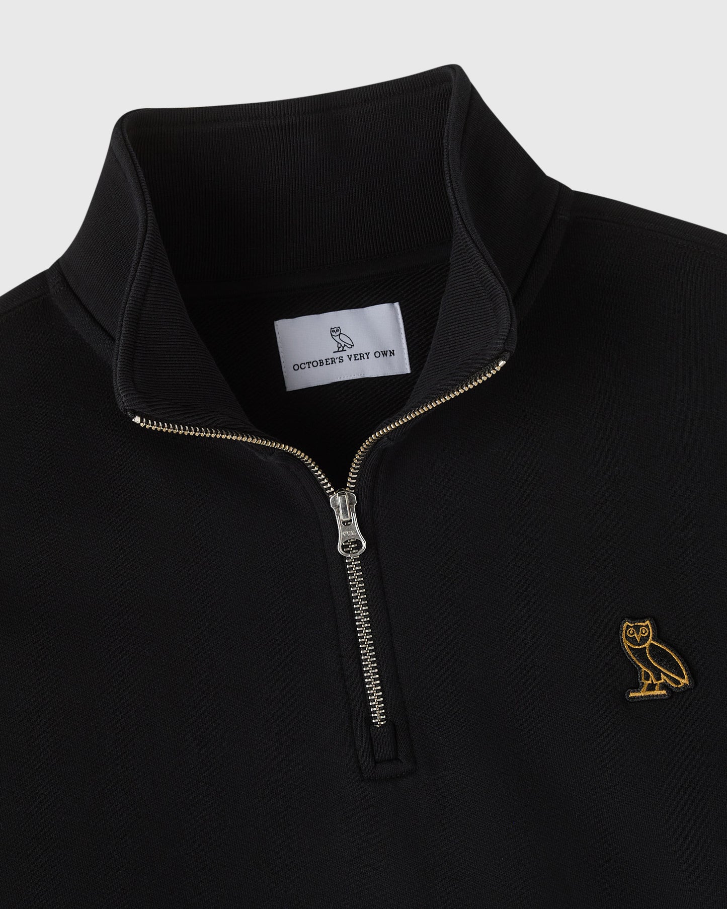 Black quarter-zip mockneck sweatshirt with gold owl embroidery on chest and metal zipper.