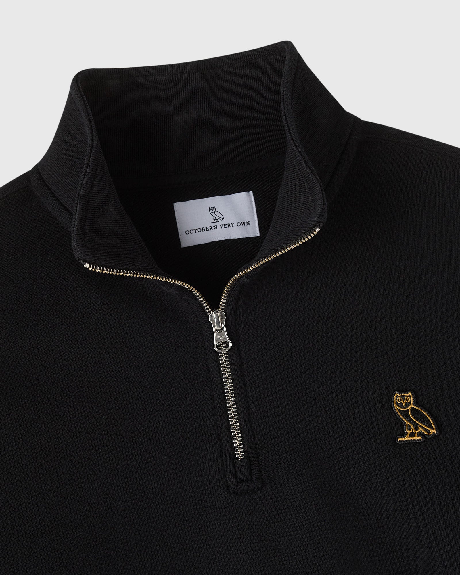 Black quarter-zip mockneck sweatshirt with gold owl embroidery on chest and metal zipper.