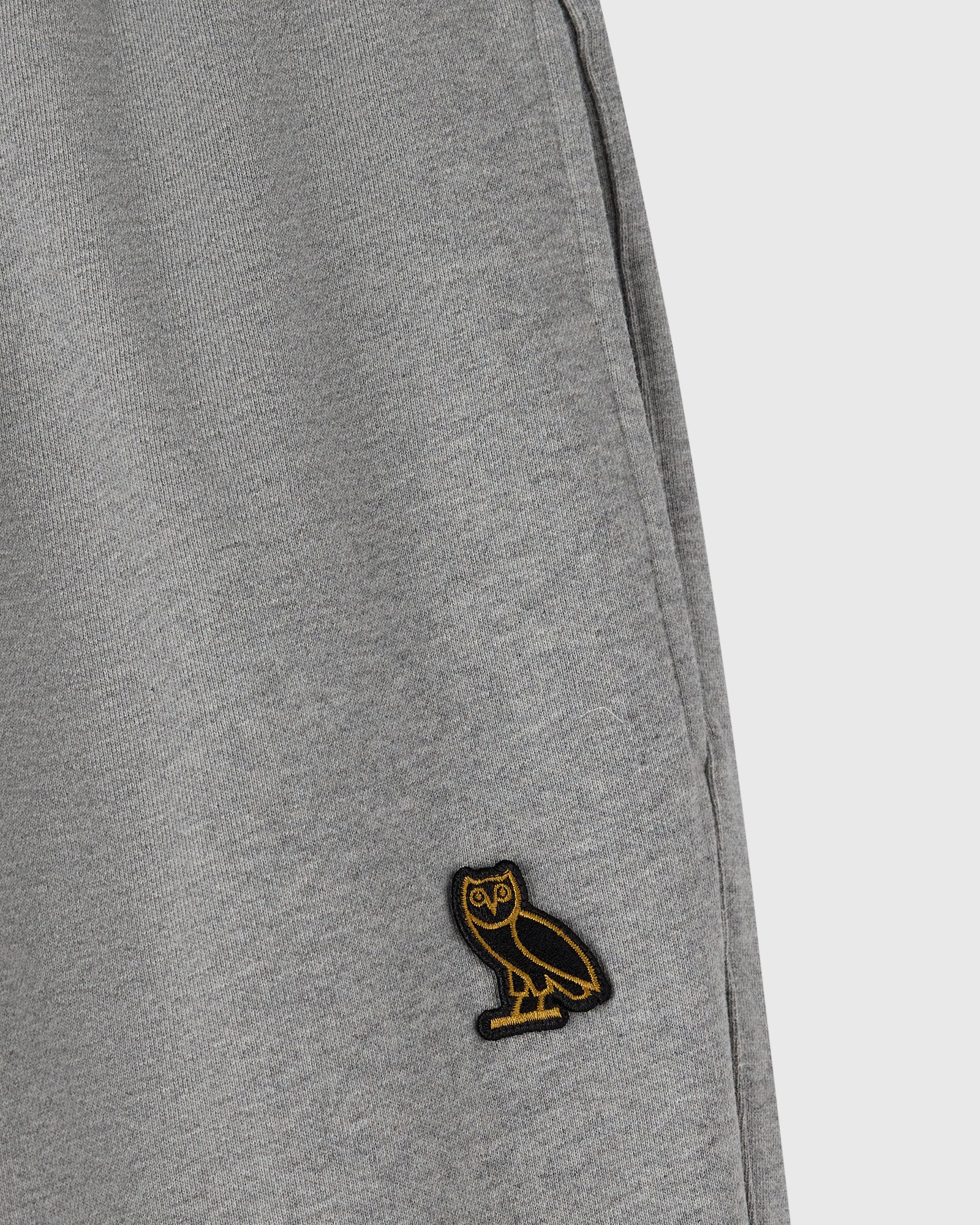 Heather grey sweatpant with ribbed texture and small embroidered owl logo on leg.