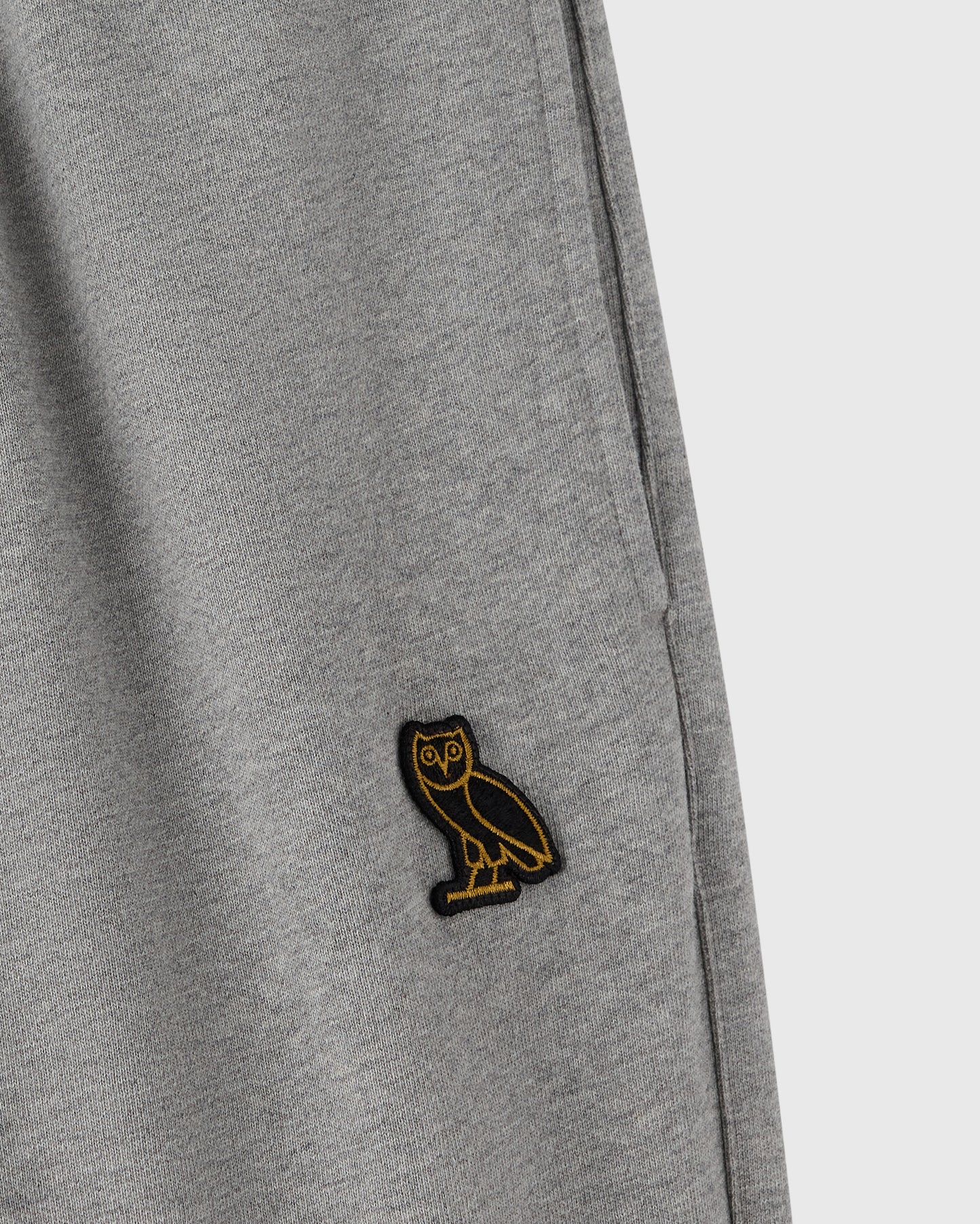 Heather grey sweatpant with small embroidered owl logo on thigh.