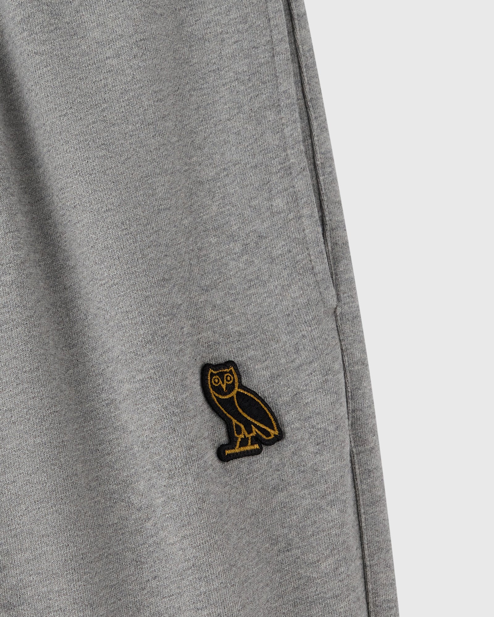 Heather grey sweatpant with small embroidered owl logo on thigh.