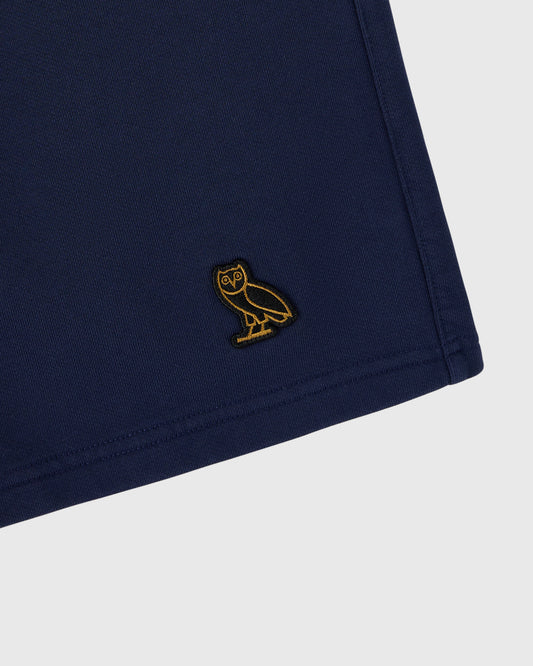Navy sweatshort with gold embroidered owl logo on thigh.