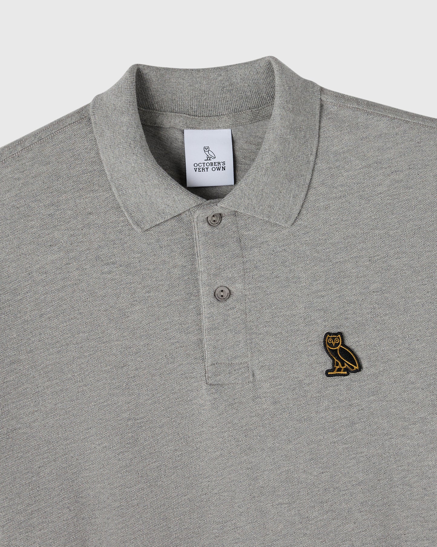 Heather grey polo shirt with ribbed collar, button placket, and small owl embroidered on chest.