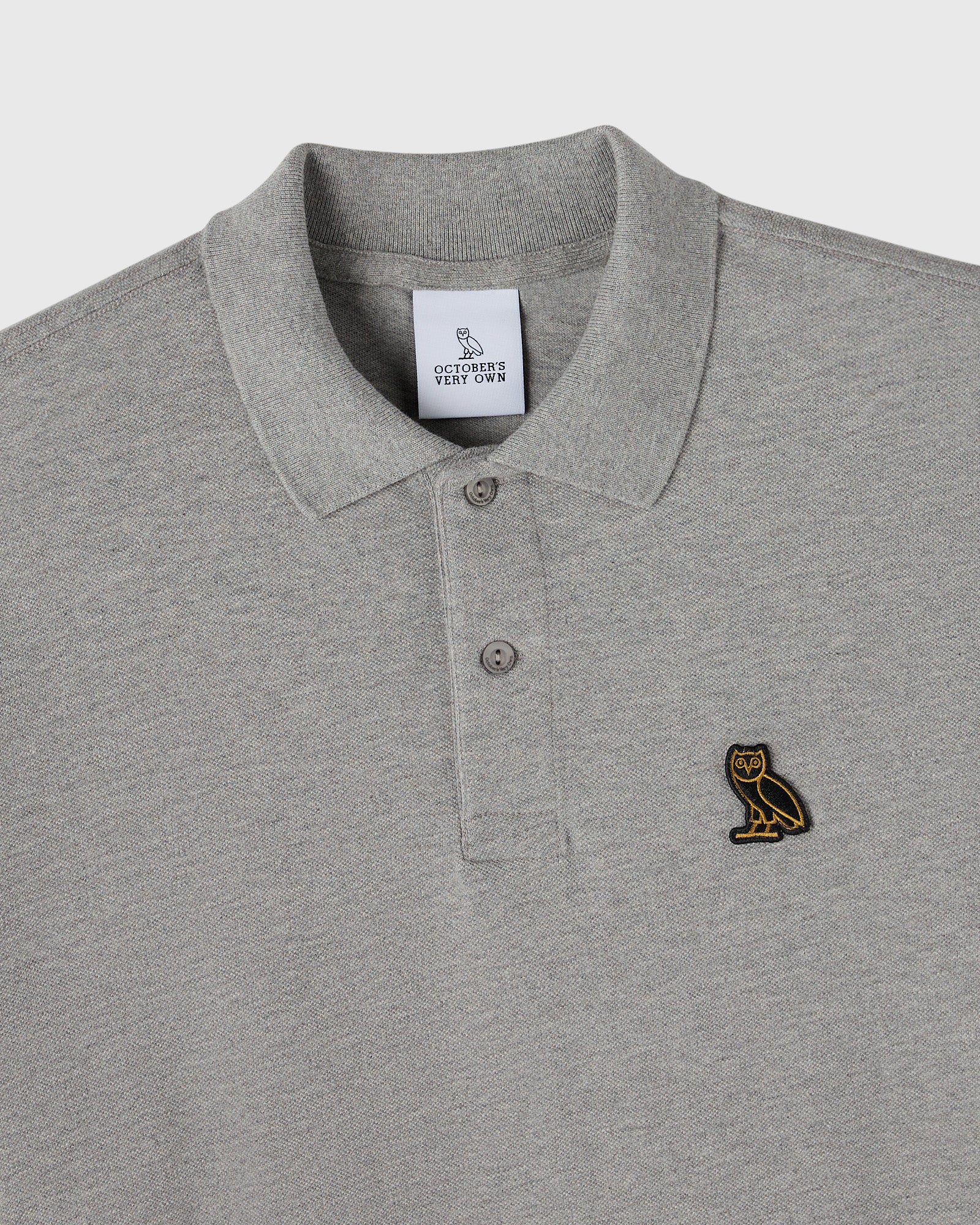 Heather grey polo shirt with ribbed collar, button placket, and small owl embroidered on chest.