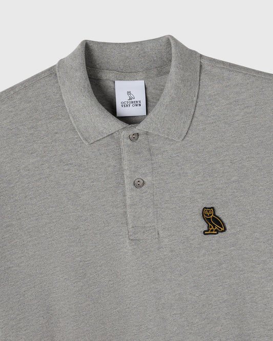 Heather grey polo shirt with ribbed collar, button placket, and small owl embroidered on chest.
