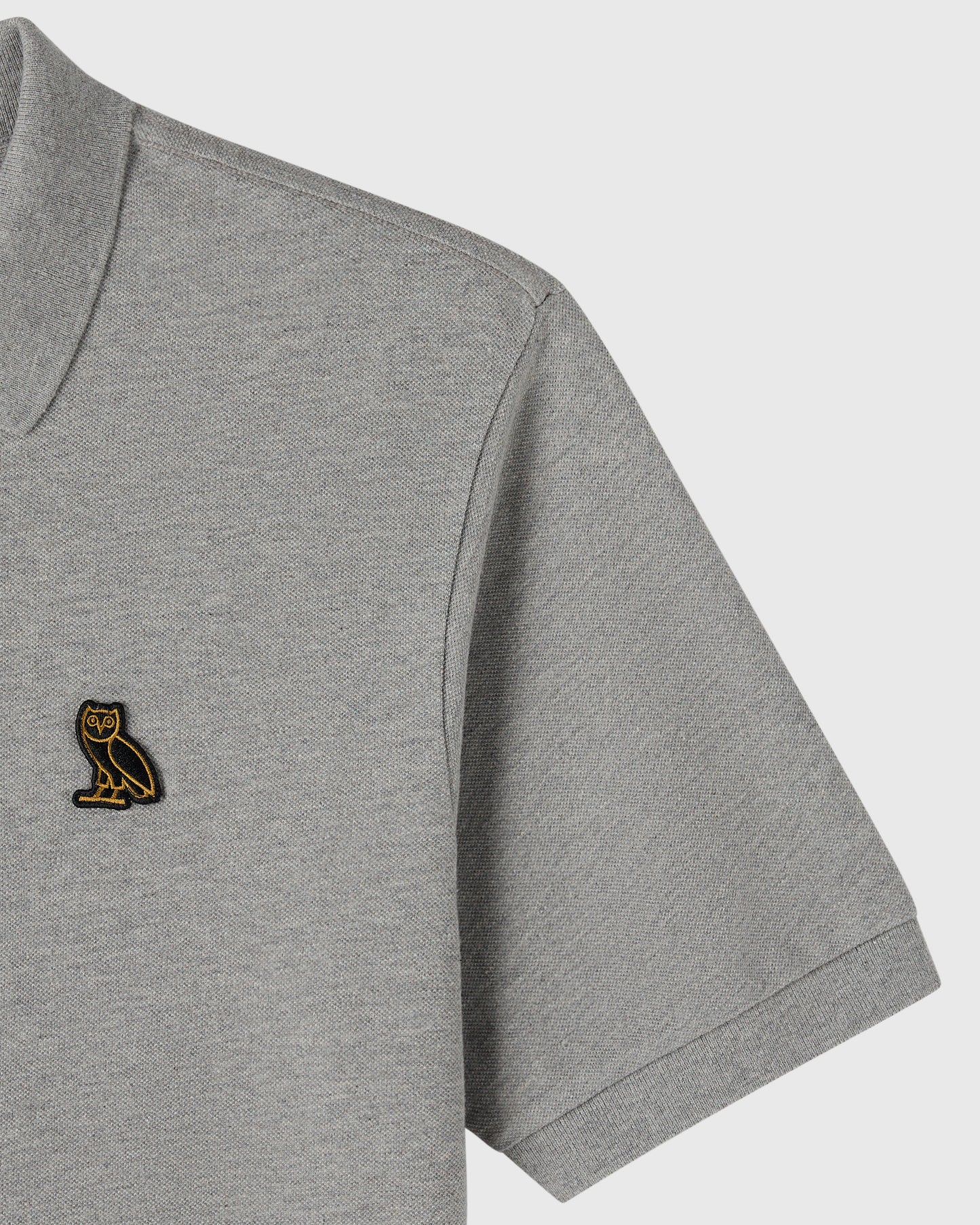 Heather grey polo shirt with small embroidered owl logo on chest and ribbed collar and cuffs.
