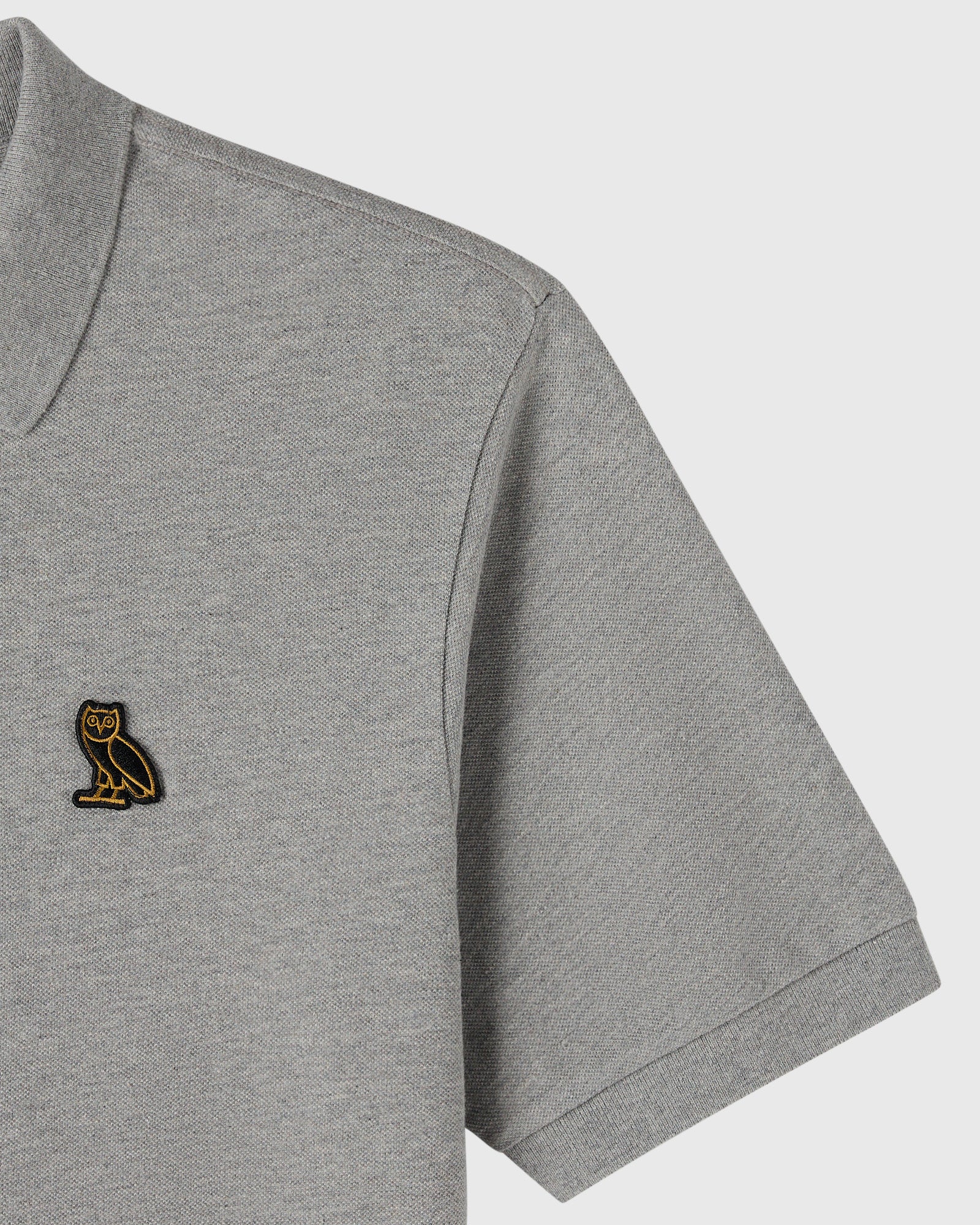 Heather grey polo shirt with small embroidered owl logo on chest and ribbed collar and cuffs.