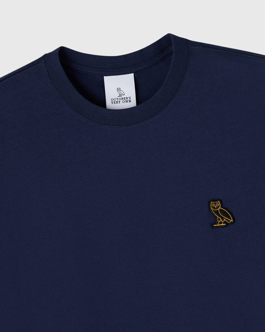 Navy crew neck t-shirt with small gold owl embroidery on chest and brand label at neckline.