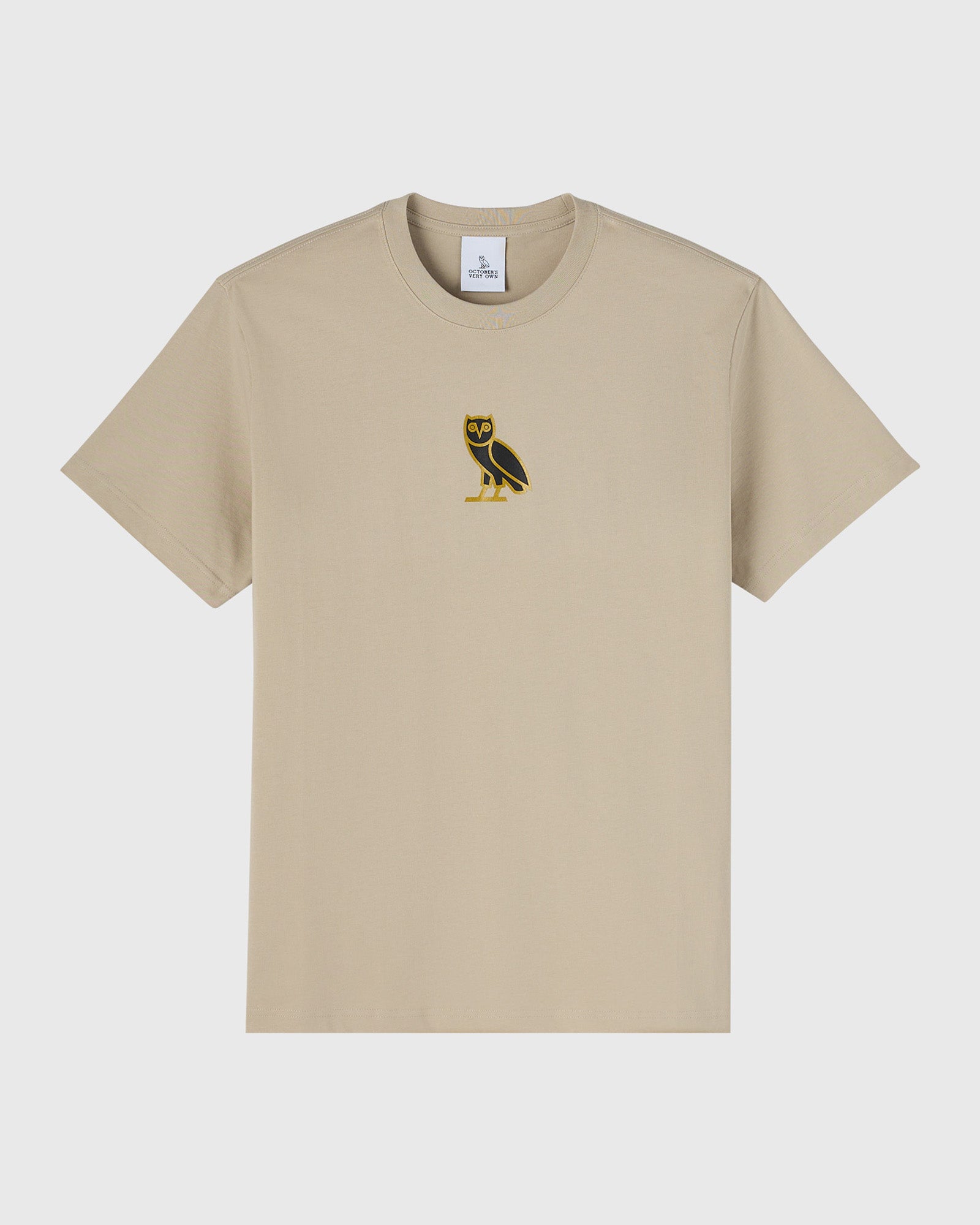 Beige short-sleeve crewneck t-shirt with small black and gold owl emblem on chest.