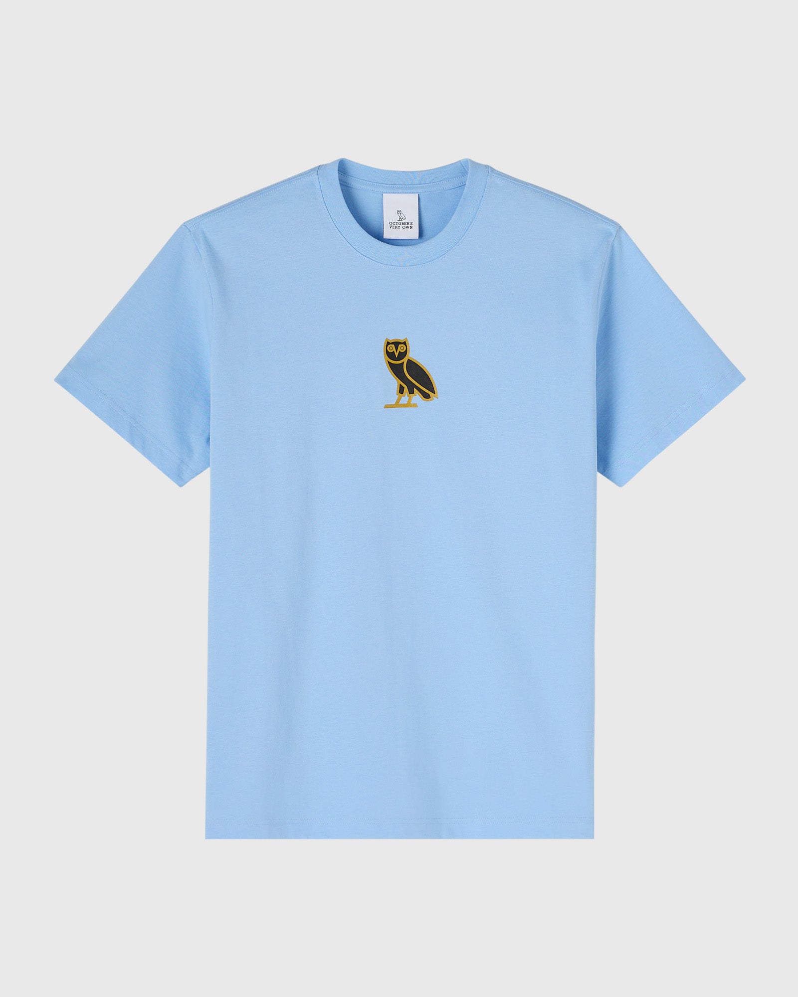 Light blue t-shirt with small black and gold owl emblem on chest.
