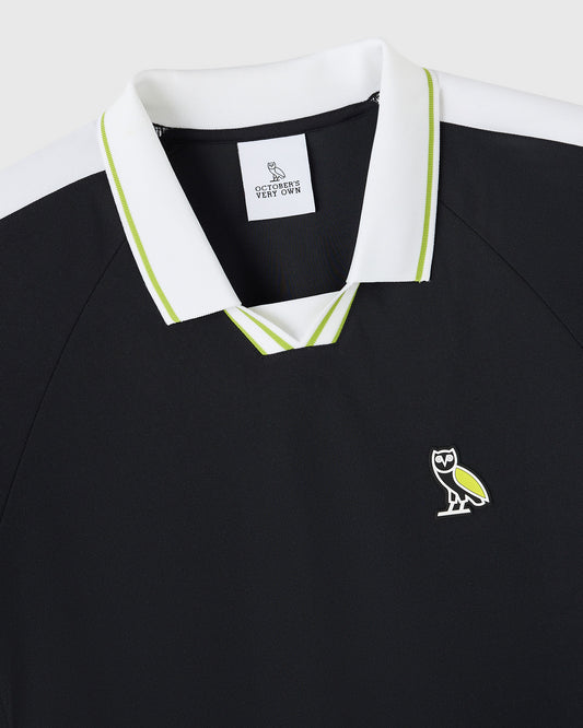 Black polo shirt with white collar, lime green tipping, and owl logo on chest.