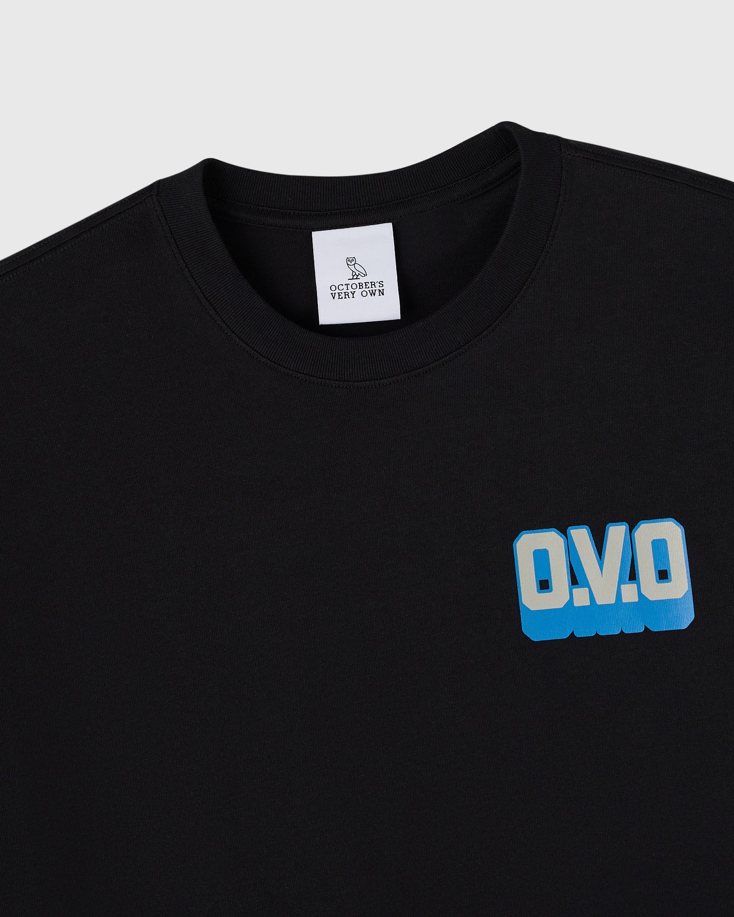 Black crewneck t-shirt with blue "O.V.O" wordmark print on chest and white brand label at neckline.